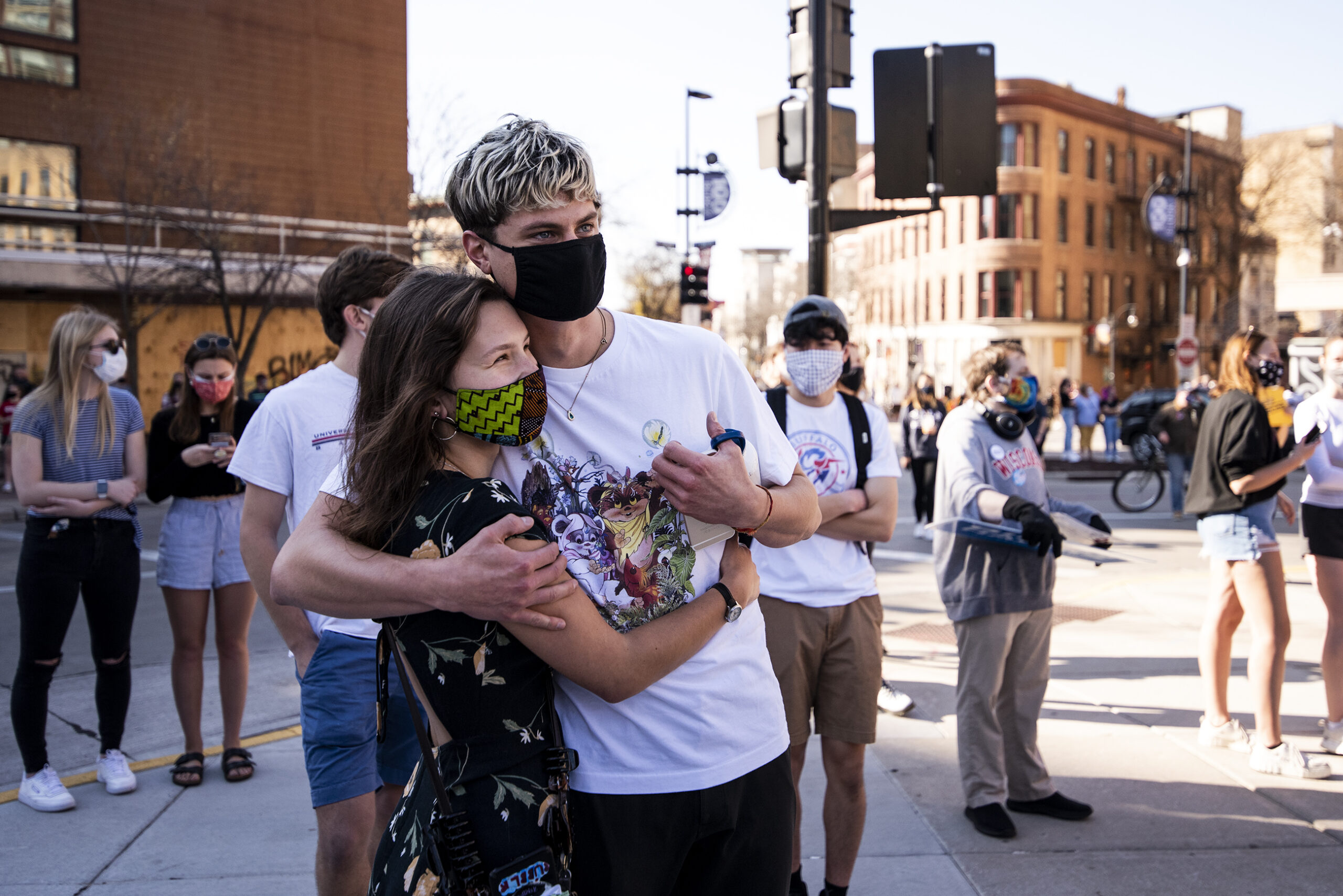 two people in face masks hug at a rally outside the Wisconsin State Capitol