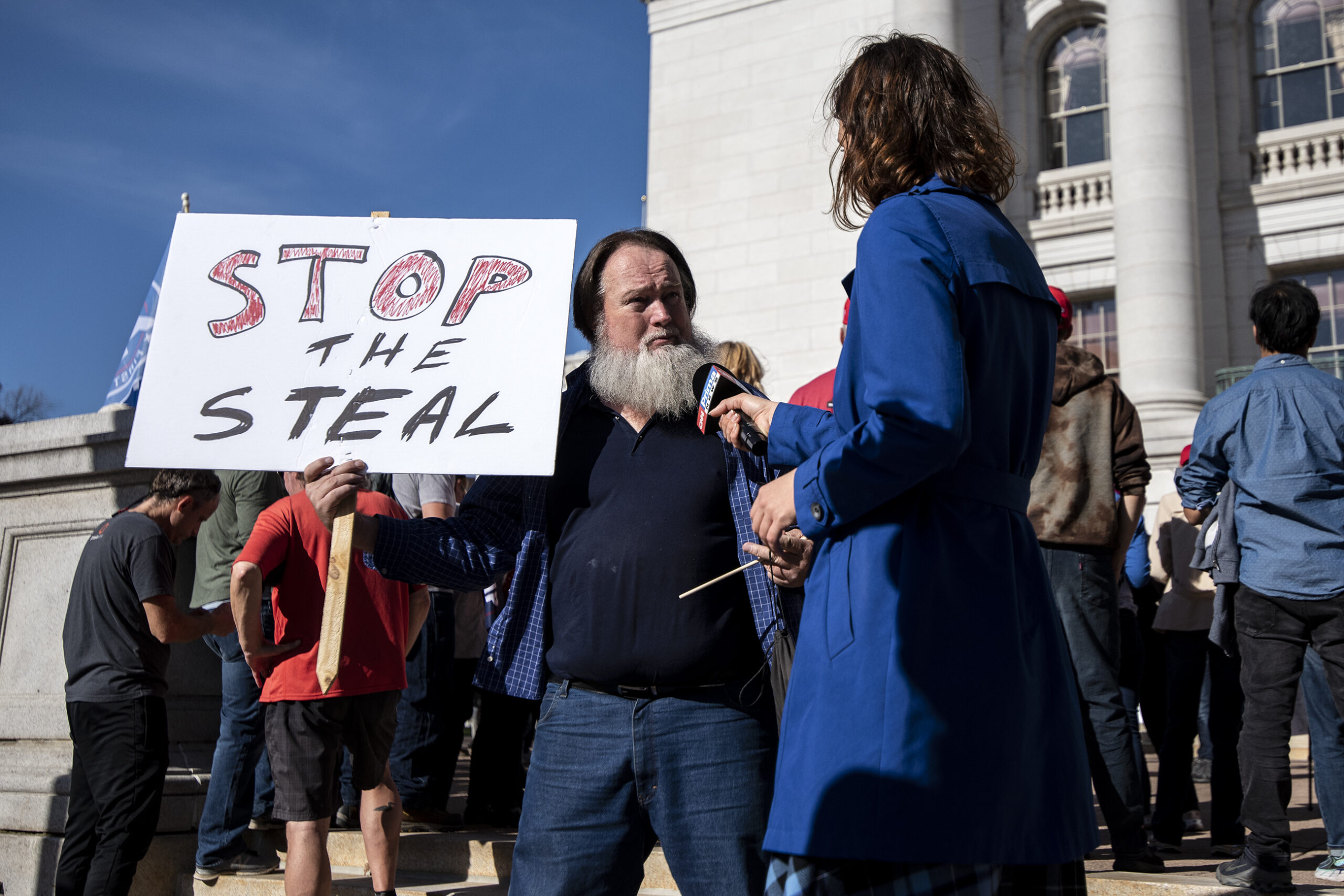 A man holds a sign that says "stop the steal"