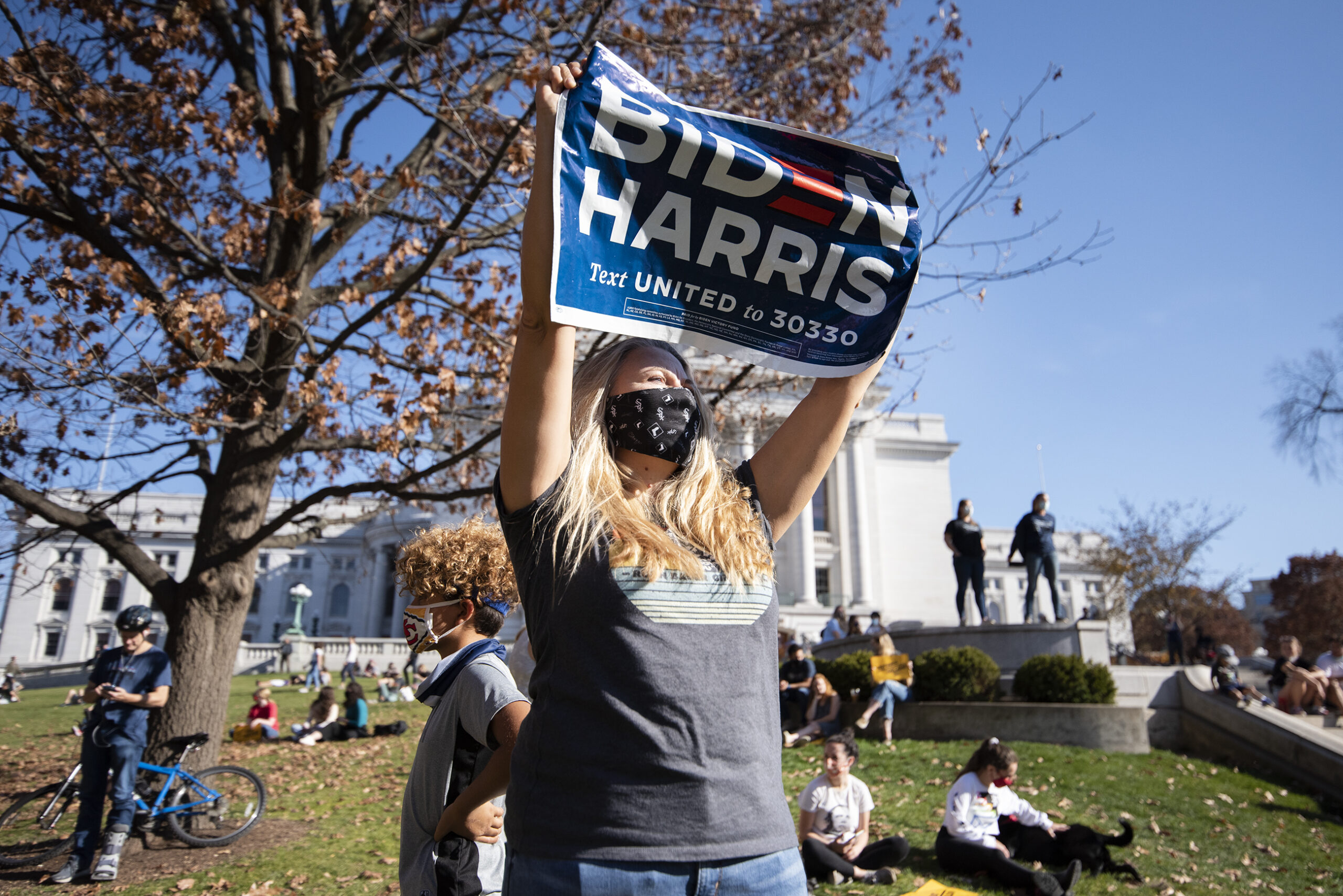 A woman holds a "Biden/Harris" sign in front of the state capitol