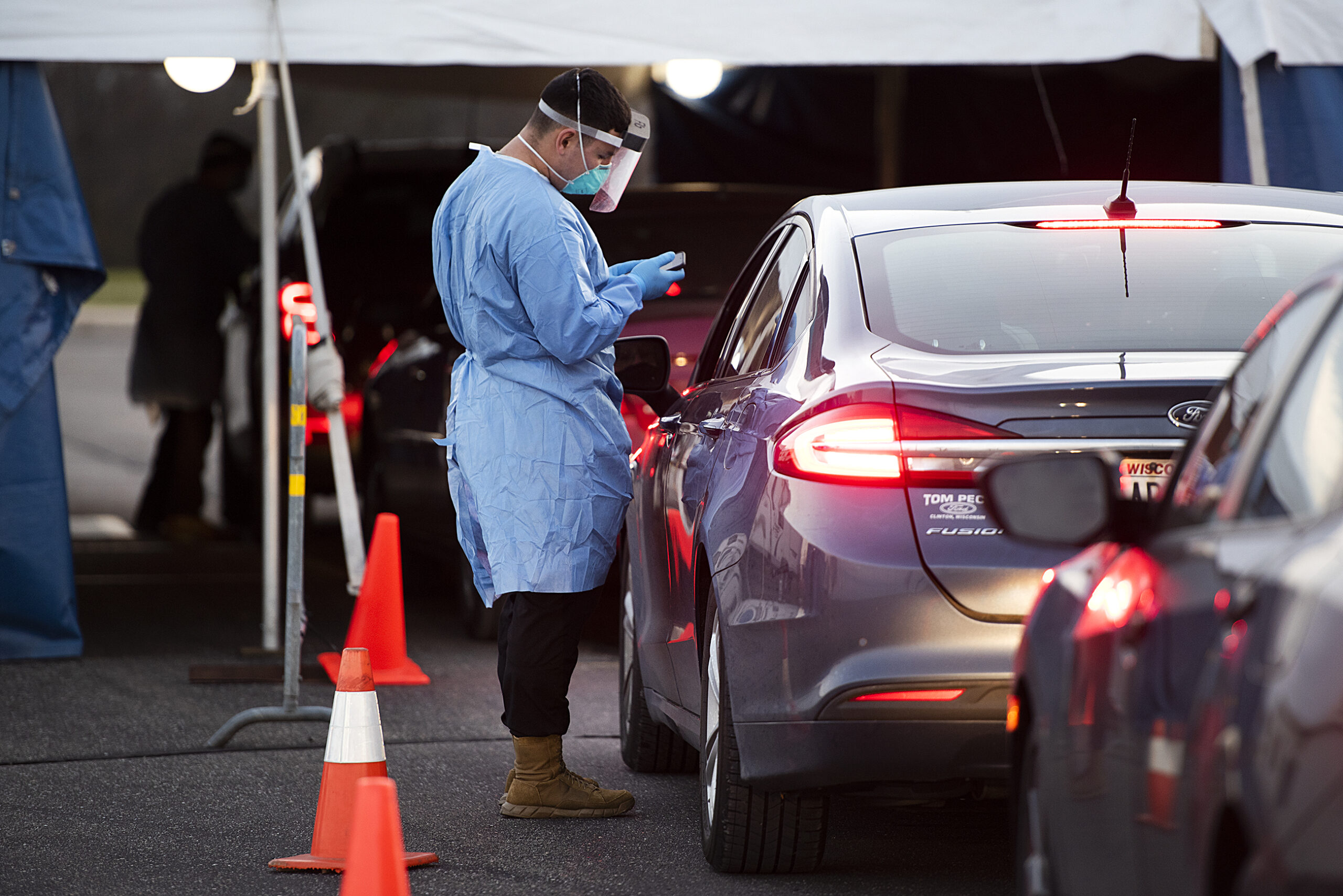 A man uses a phone to enter information for COVID-19 testing