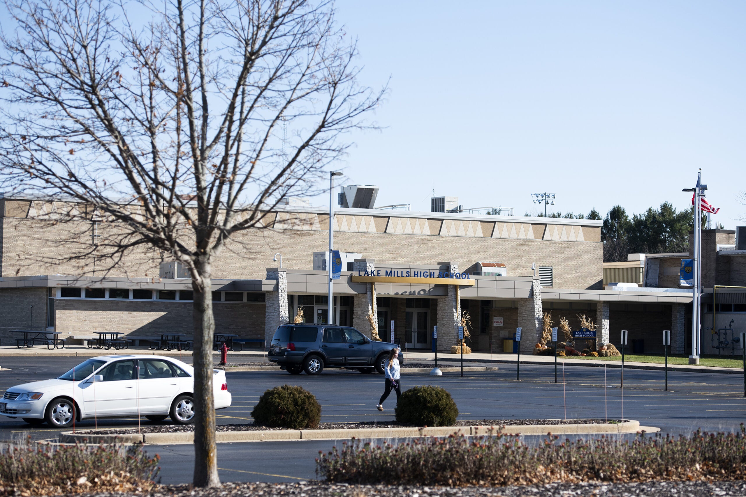 A person walks in the parking lot in front of Lake Mills High School.