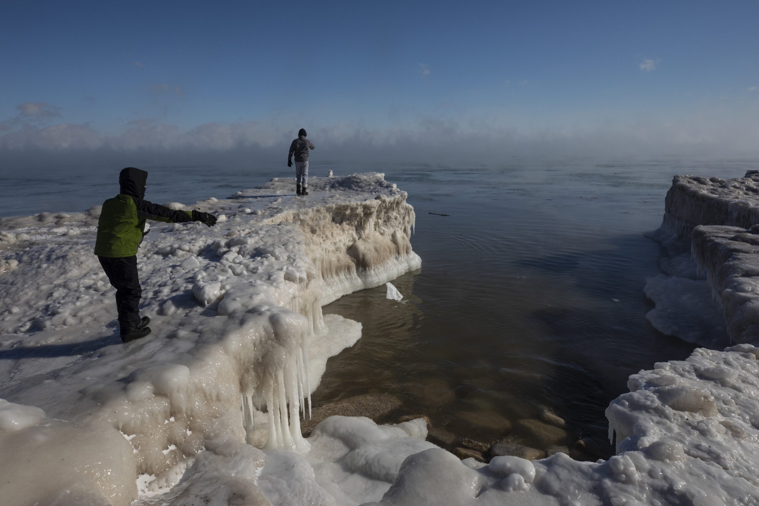 A young boy tosses a chunk of snow into Lake Michigan