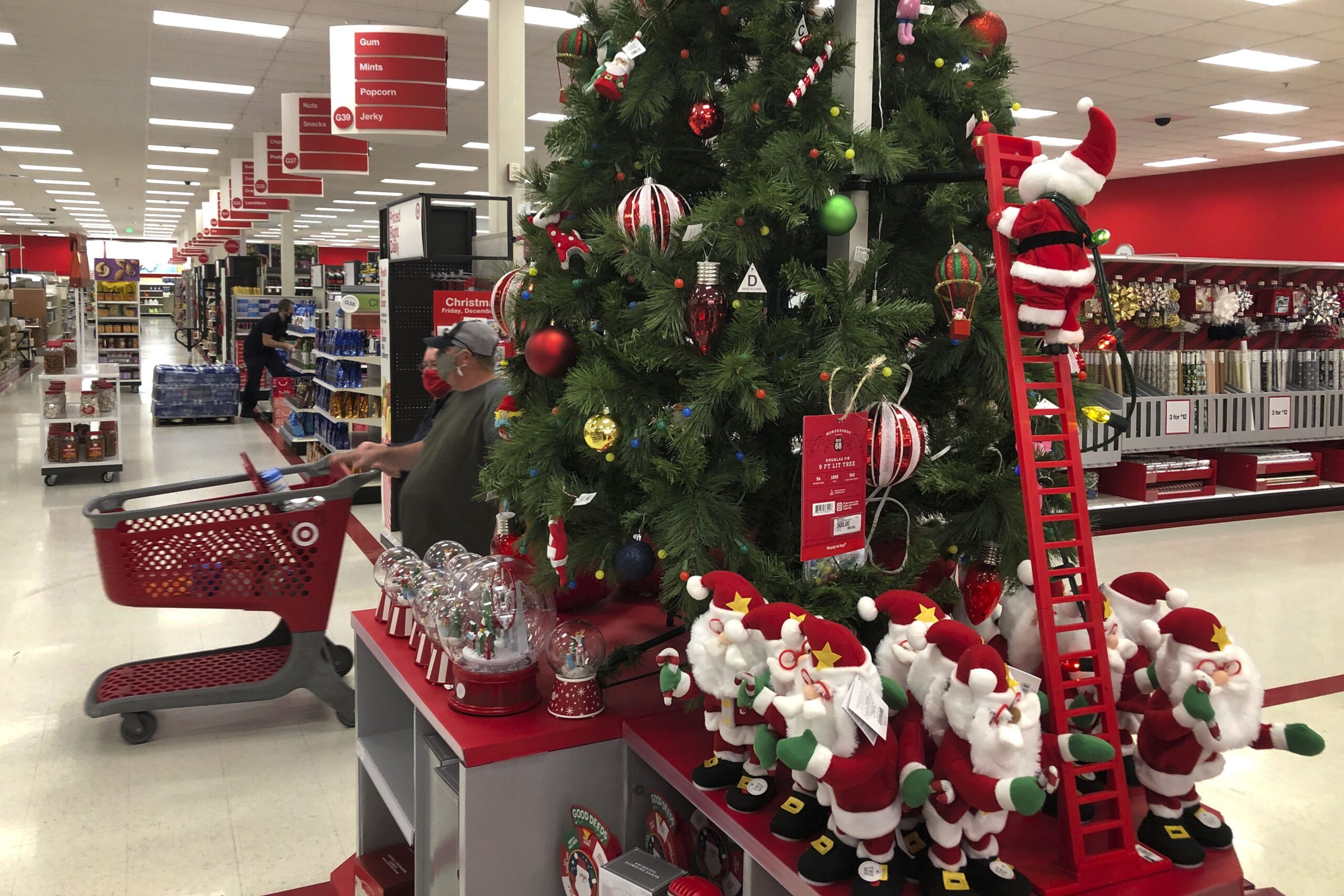 Shoppers wearing masks walk past a display of Christmas decorations at a Target store