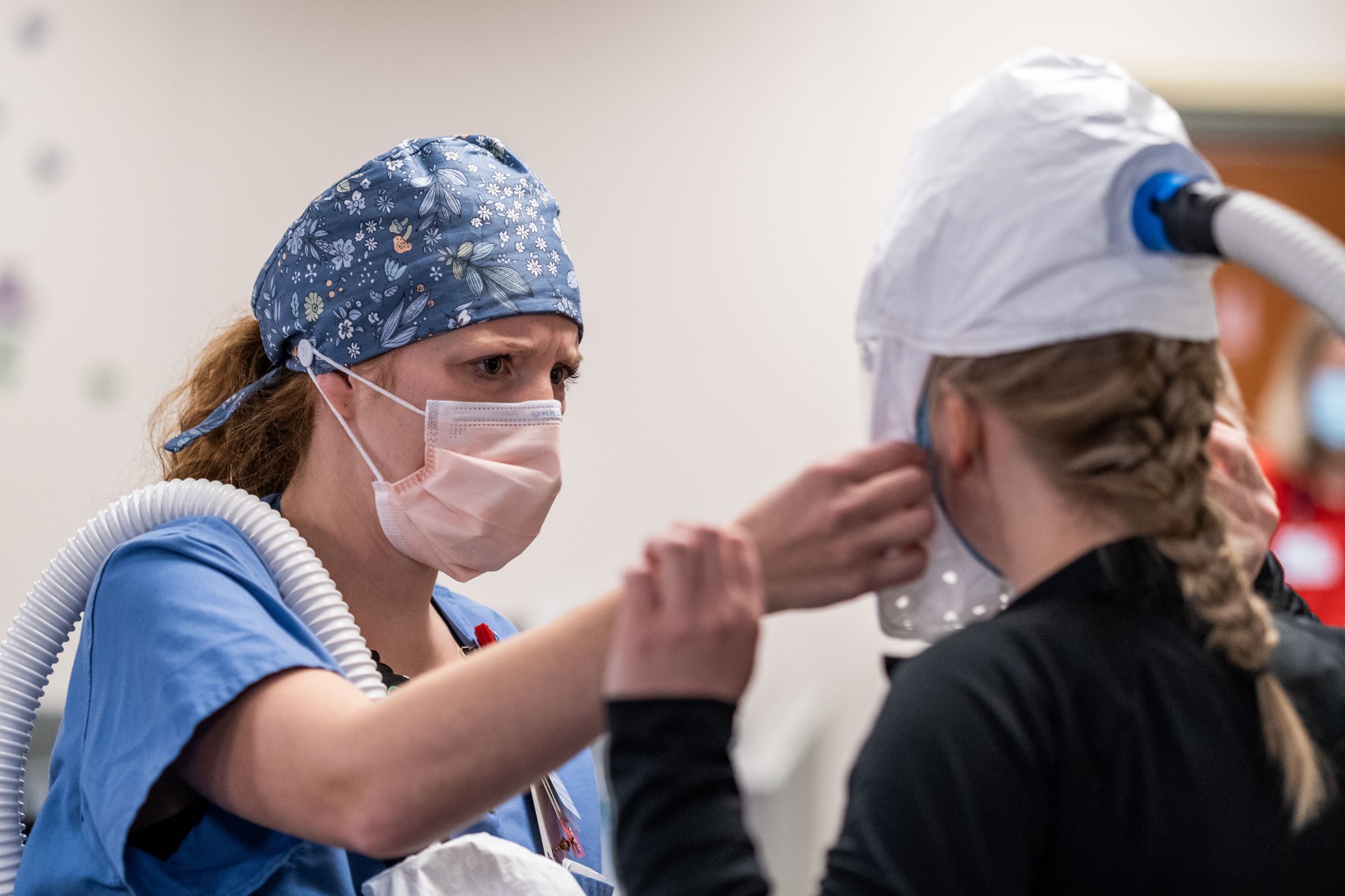 A healthcare worker helps a colleague adjust her personal protective equipment