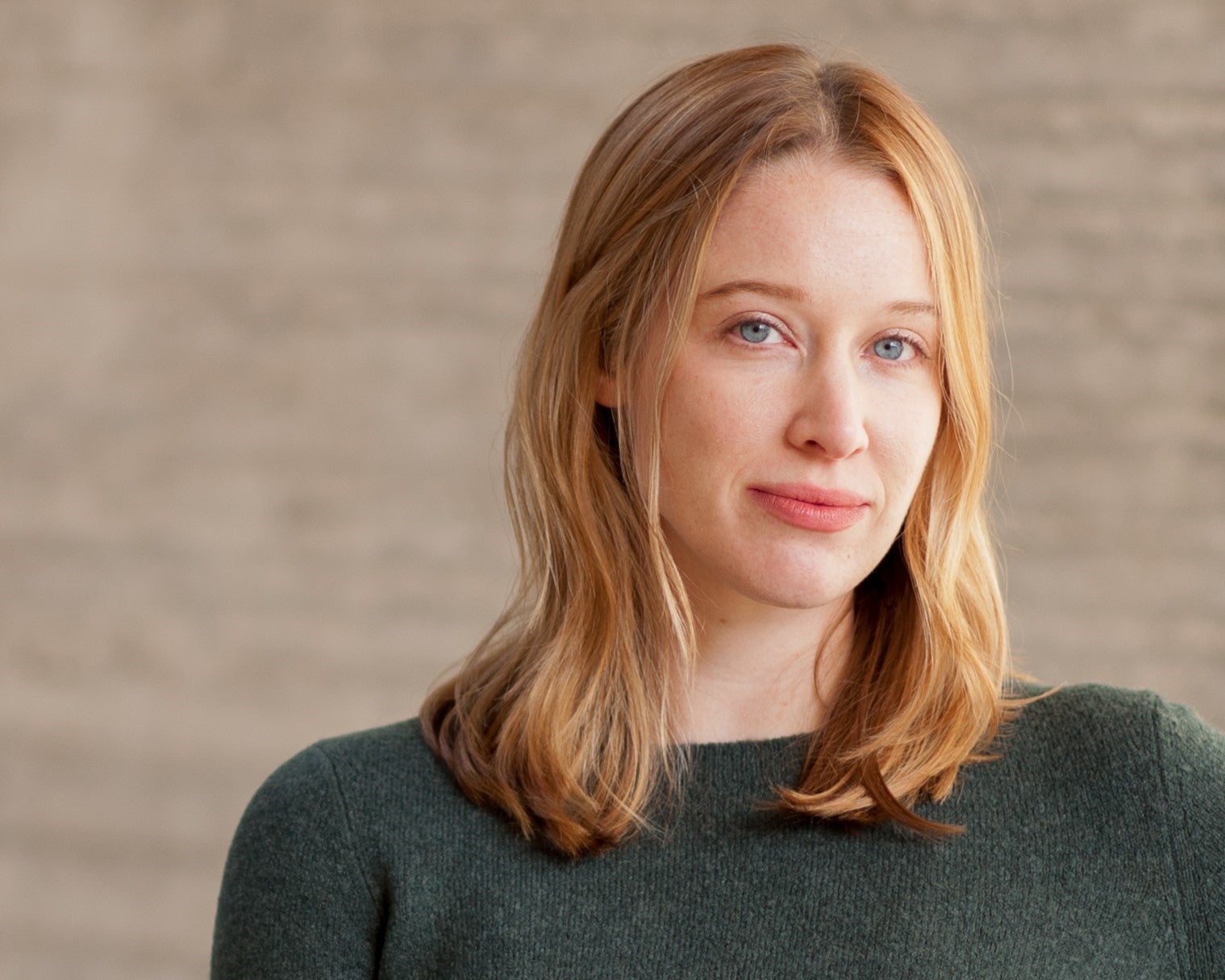 Author Chloe Benjamin headshot wearing a forest green sweater against a muted, beige background.