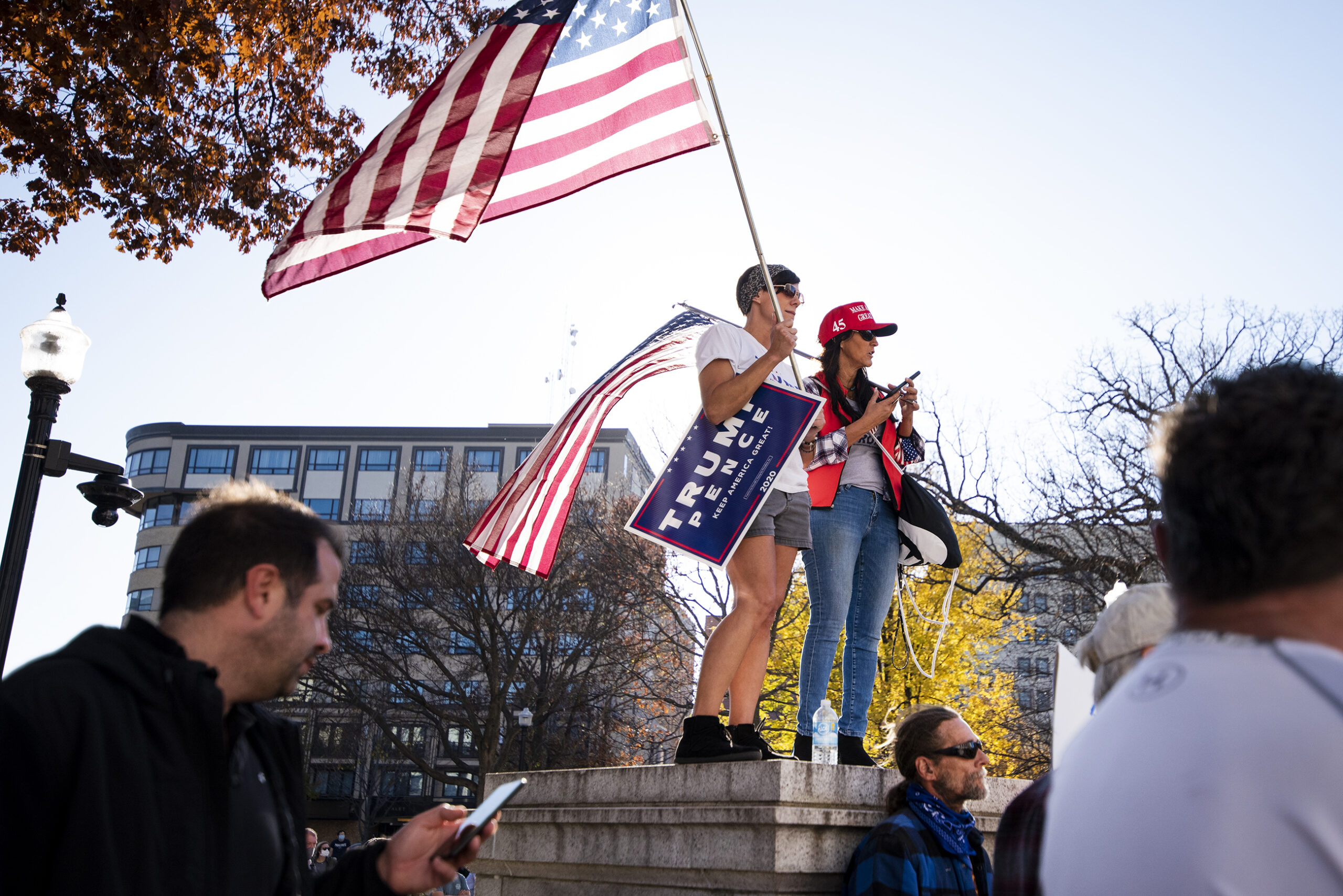 Trump supporters stand on a ledge holding Trump signs and U.S. flags