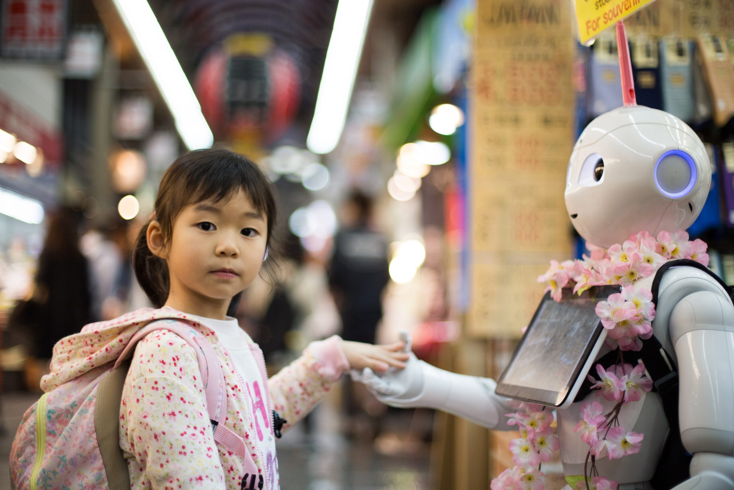 A girl greeting a robot in a Japanese market