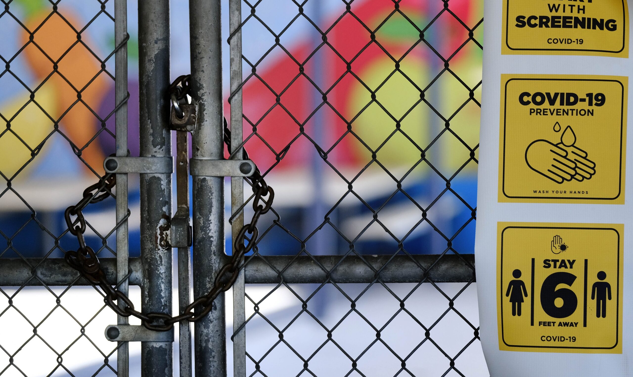 a chain-link fence lock is seen on a gate at a closed elementary school