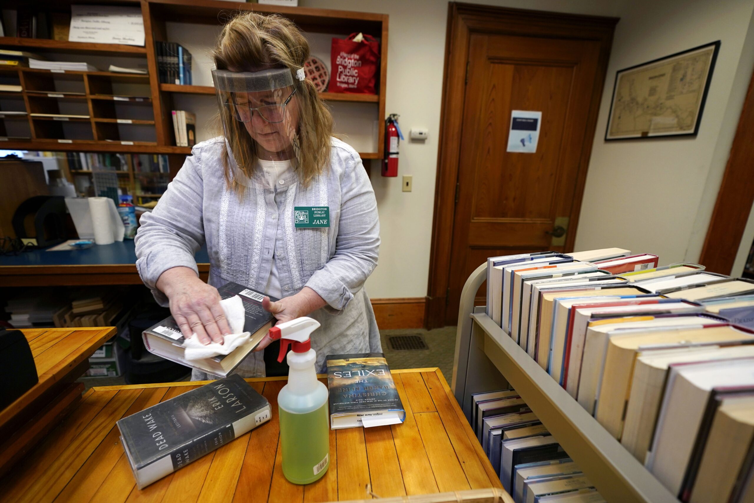 Jane Whitworth, circulation manager for the Bridgton Public Library, wears a face shield while disinfected recently returned books