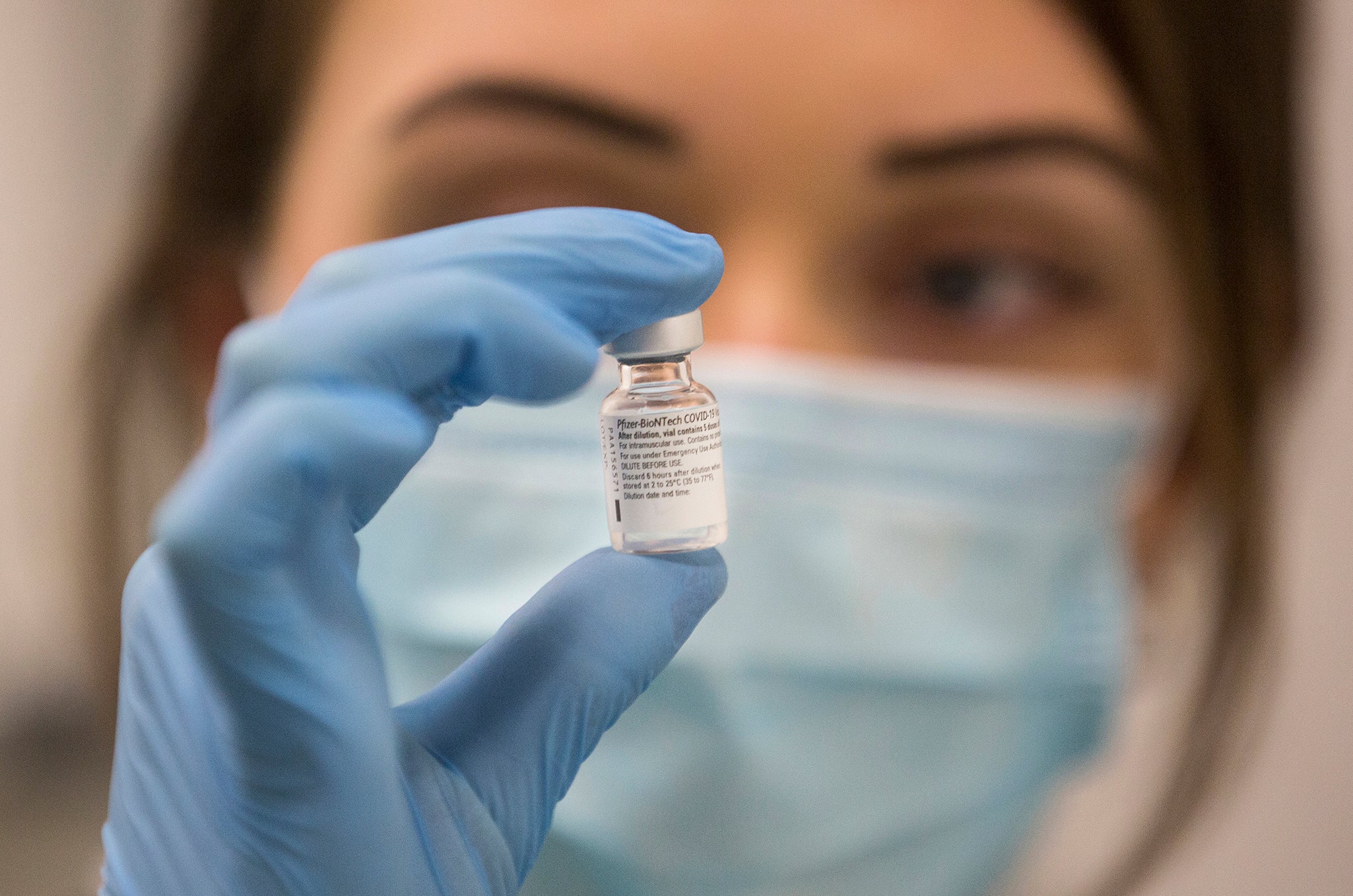 A worker holds a bottle of the Pfizer-BioNTech COVID-19 vaccine