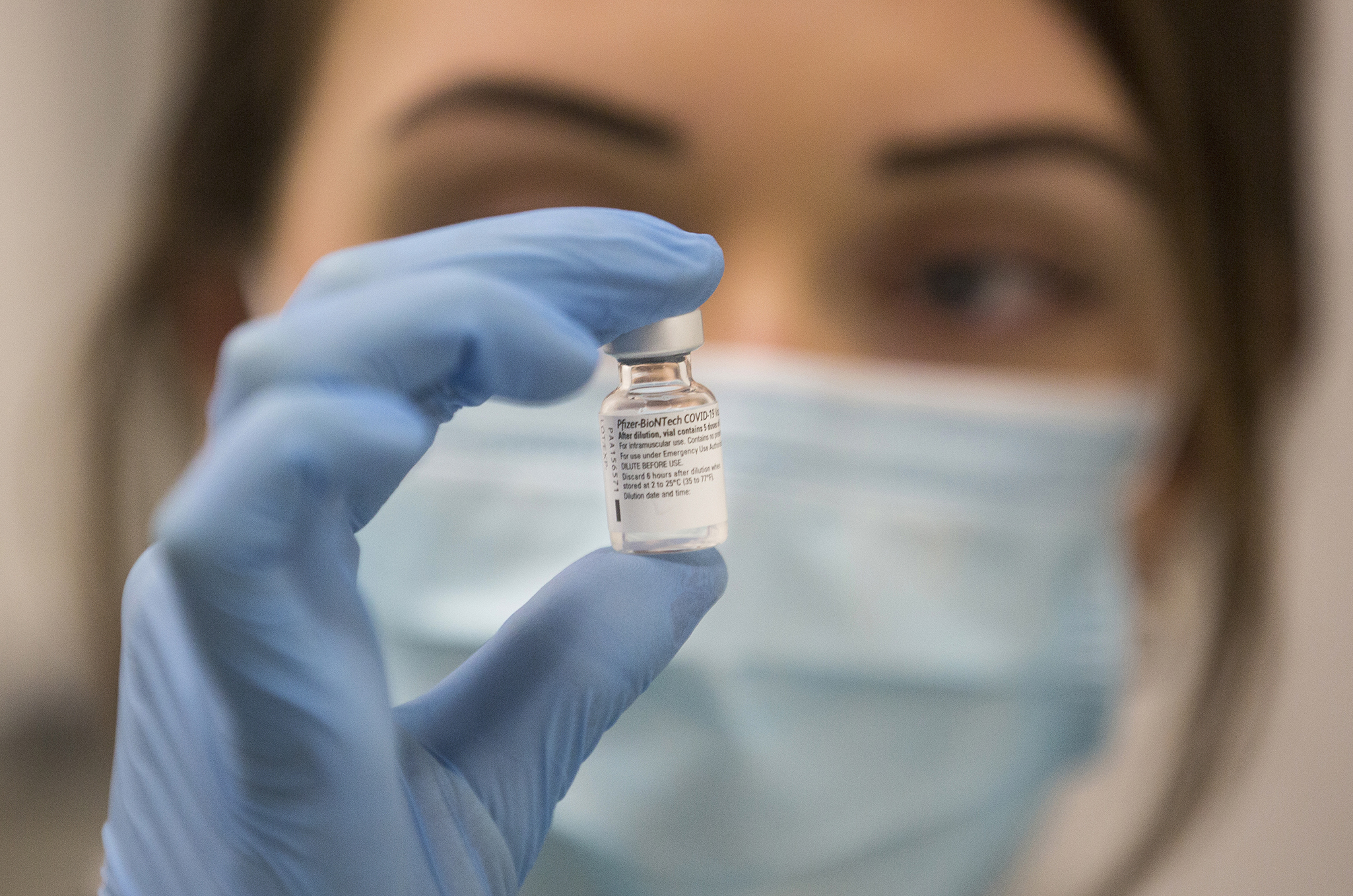 A worker holds a bottle of the Pfizer-BioNTech COVID-19 vaccine