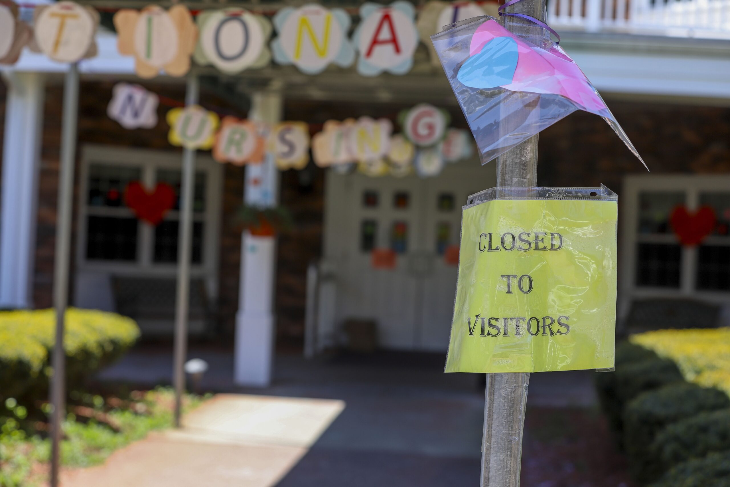 A sign posted near the entrance to a nursing home shows the home closed to visitors