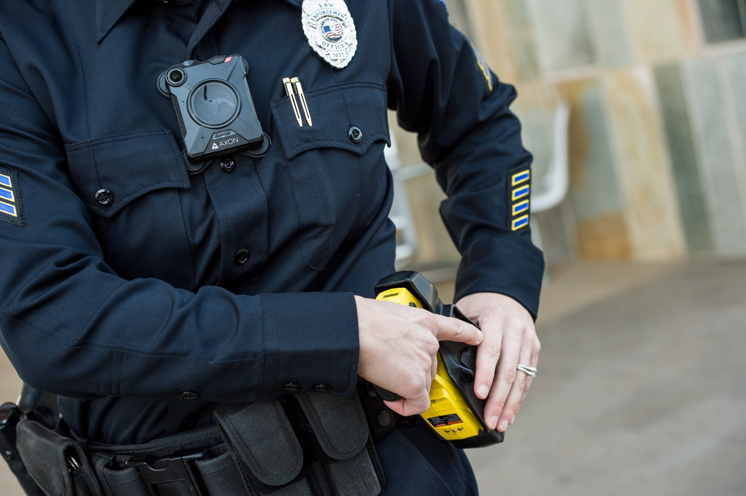 An officer reaches for their taser while wearing a body camera