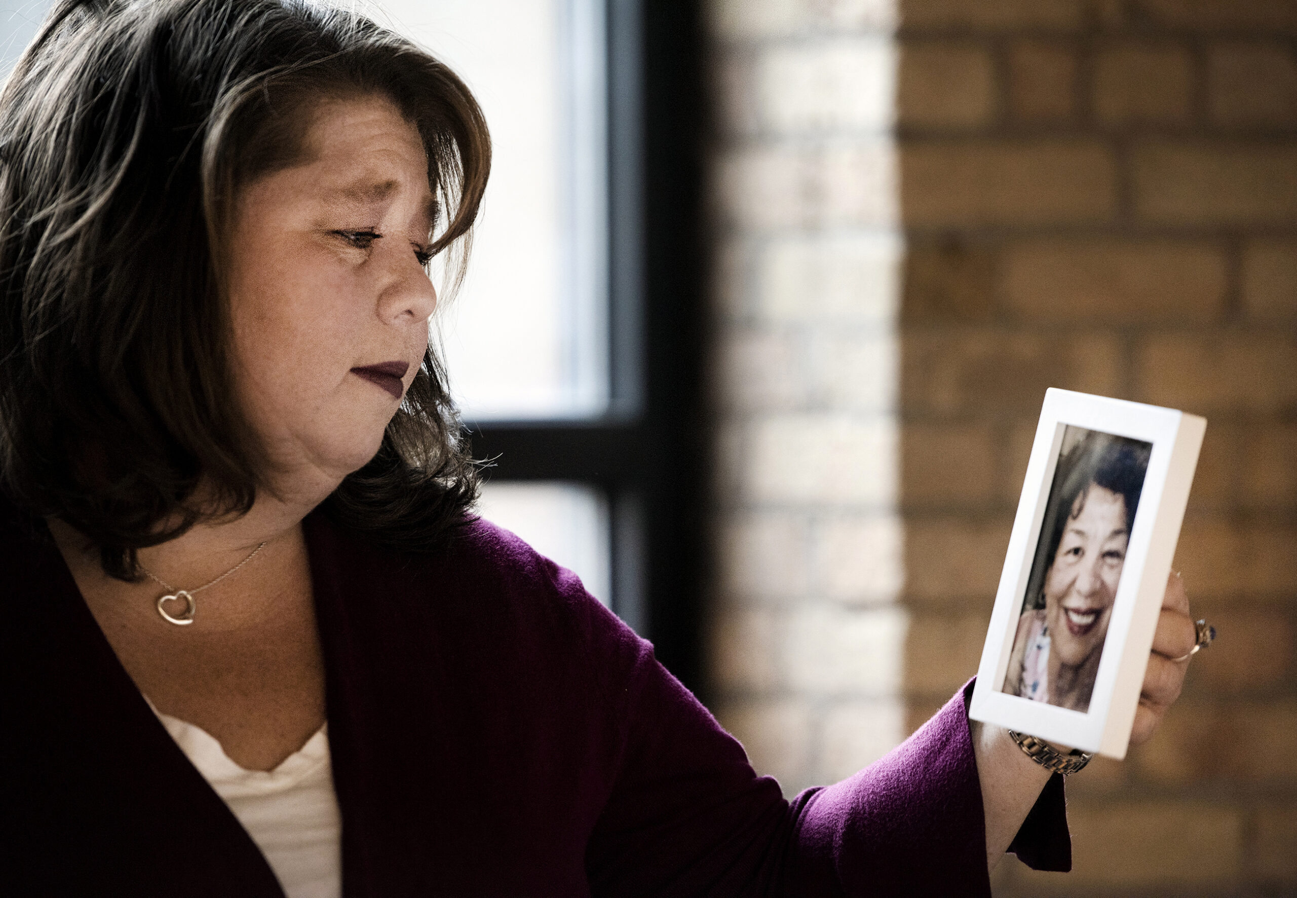 A woman looks at a photo in her hand showing her mother