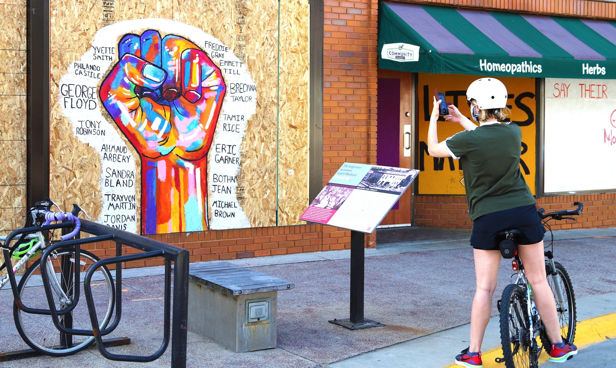 A bicyclist takes a photo of protest art