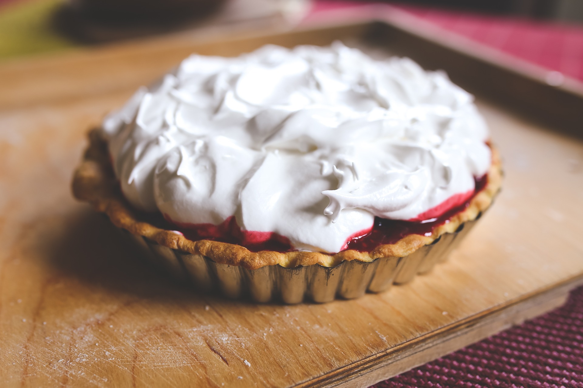 A pie with cream topping sits on a wood table