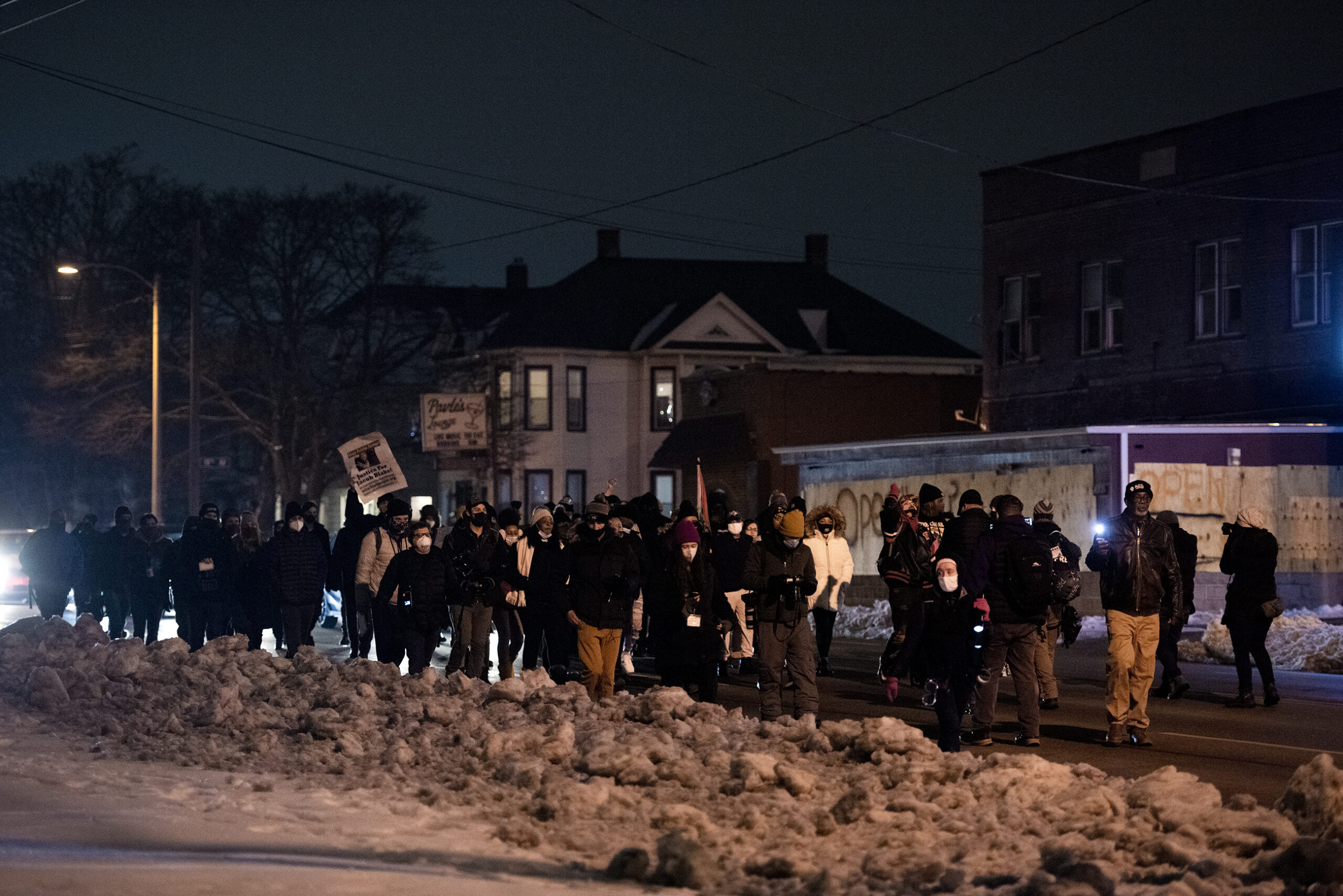 piles of dirty snow line the streets where protesters march at night