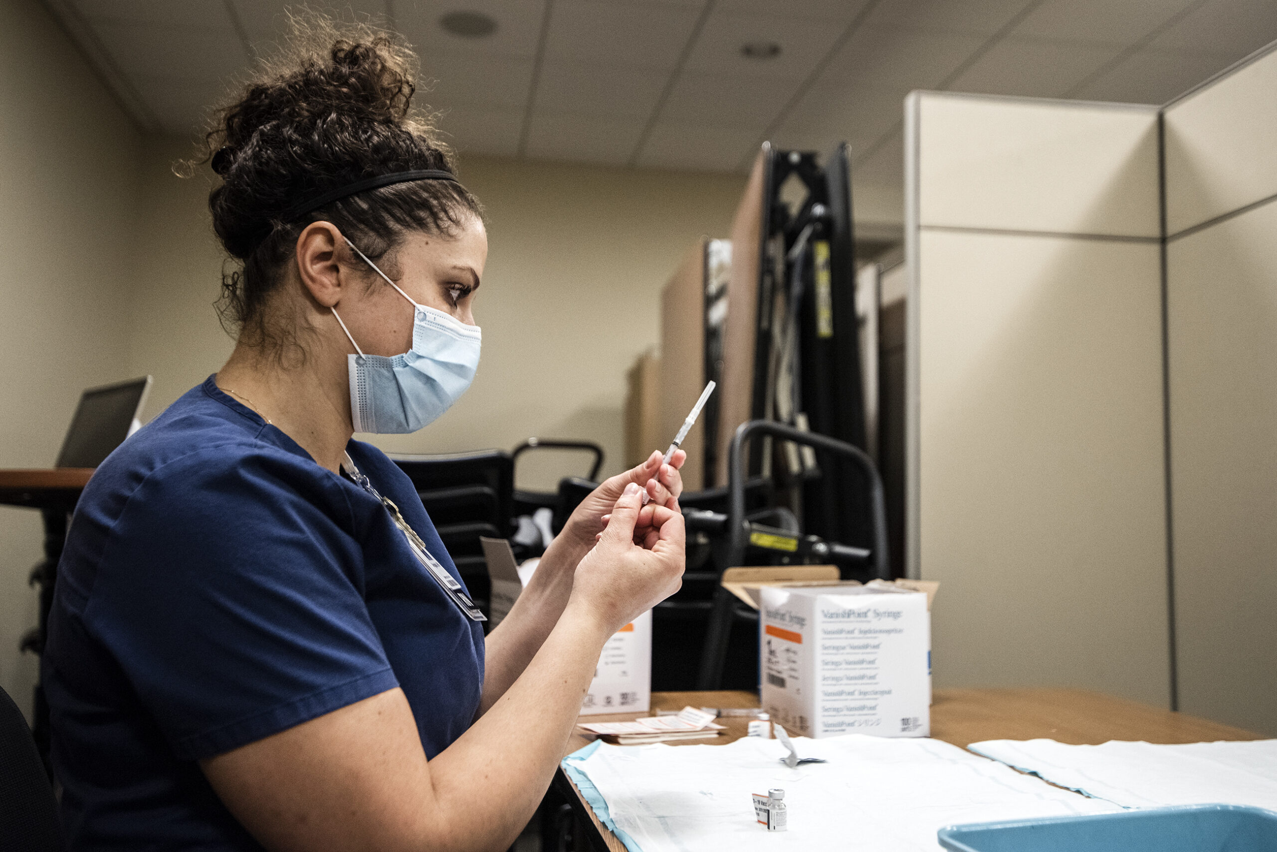 A healthcare worker pushes the vaccine into a syringe