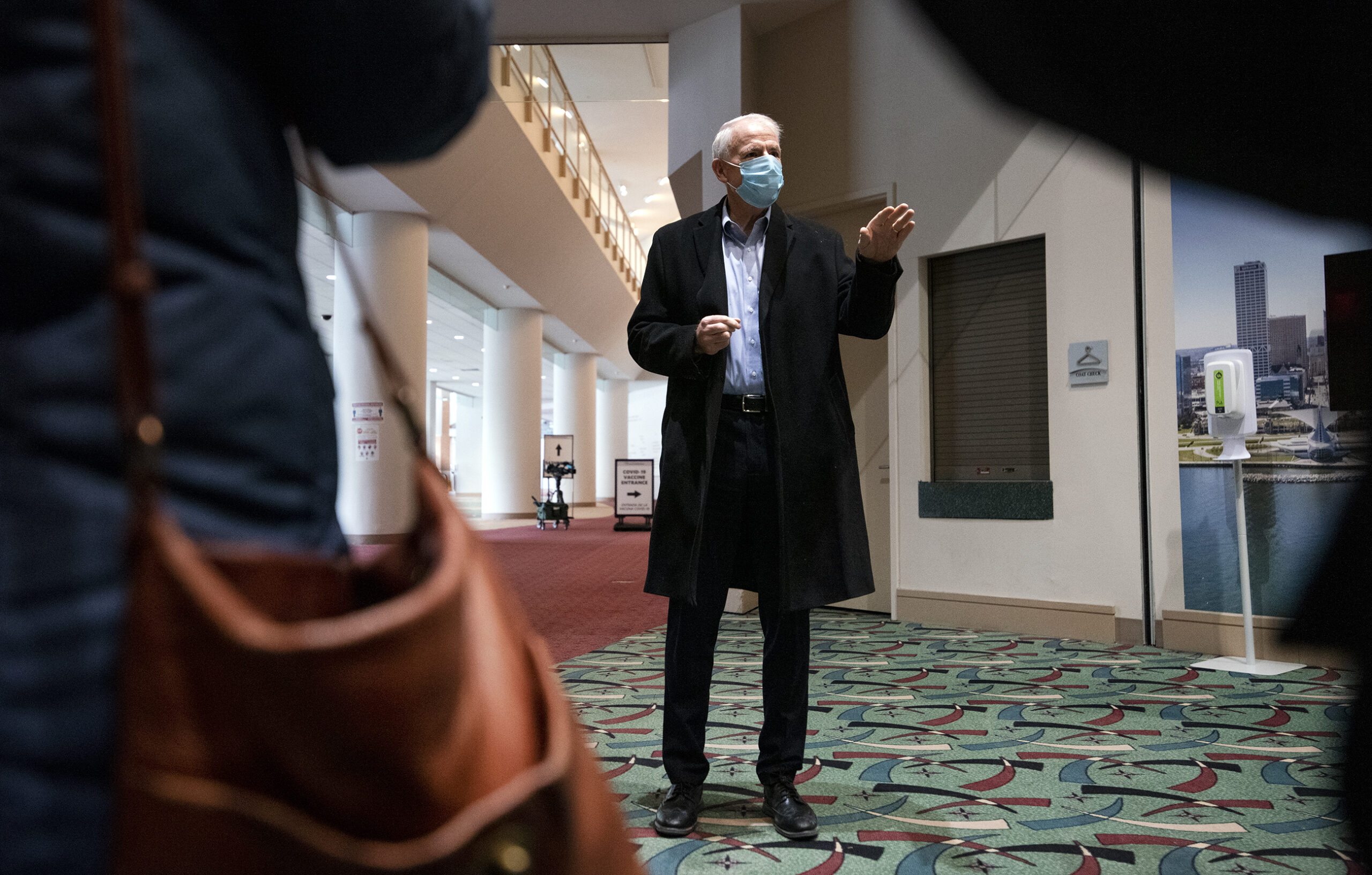 Tom Barrett gestures as he speaks to reporters wearing a face mask