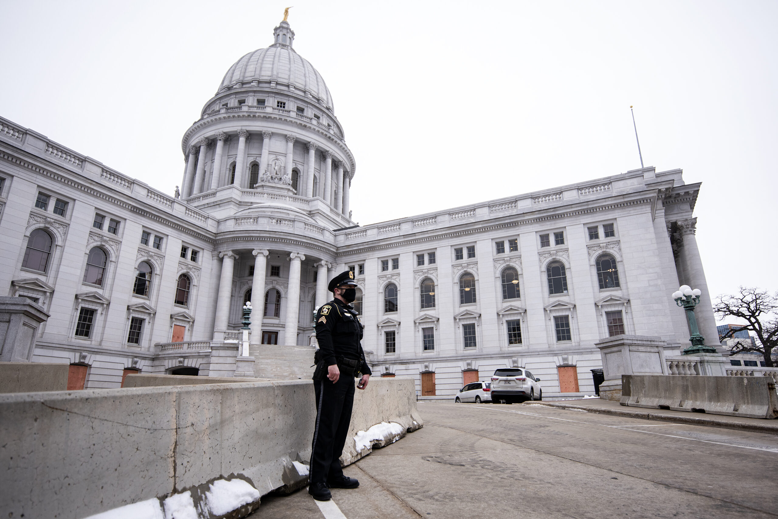 a police officer in uniform stands in front of a barrier at the Wisconsin State Capitol