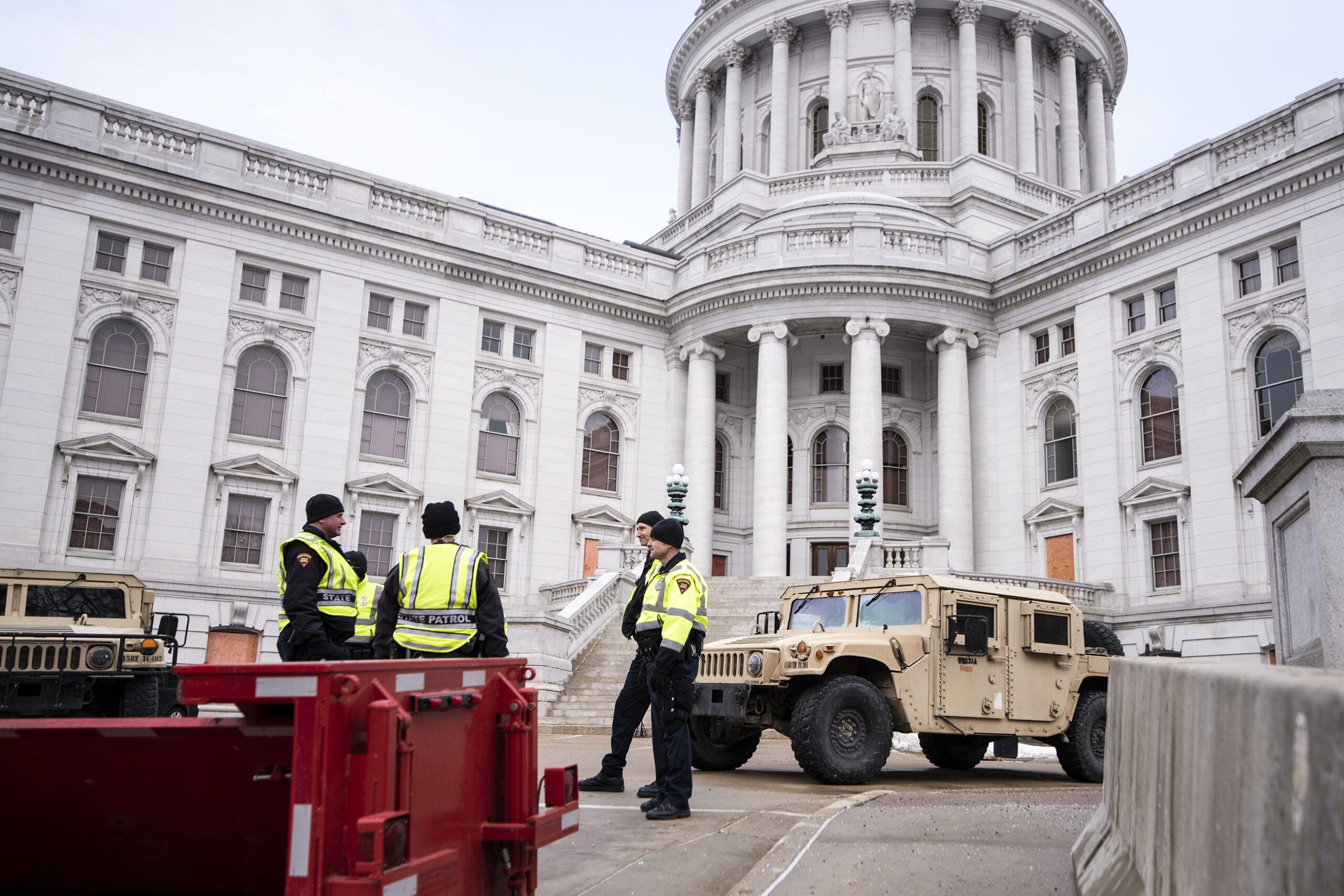 Police in neon vests stand near a national guard vehicle outside the capitol
