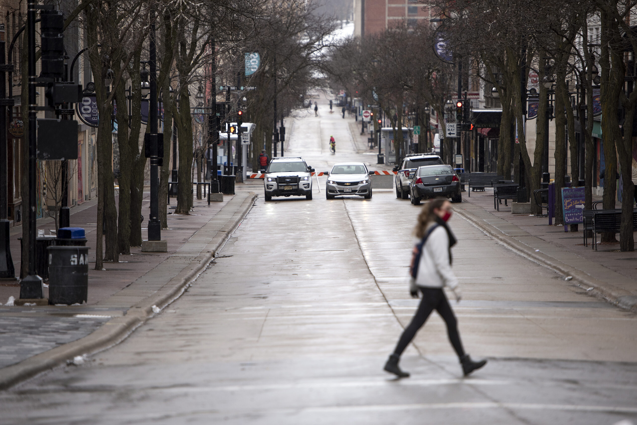 A person walks across a street blocked off by police