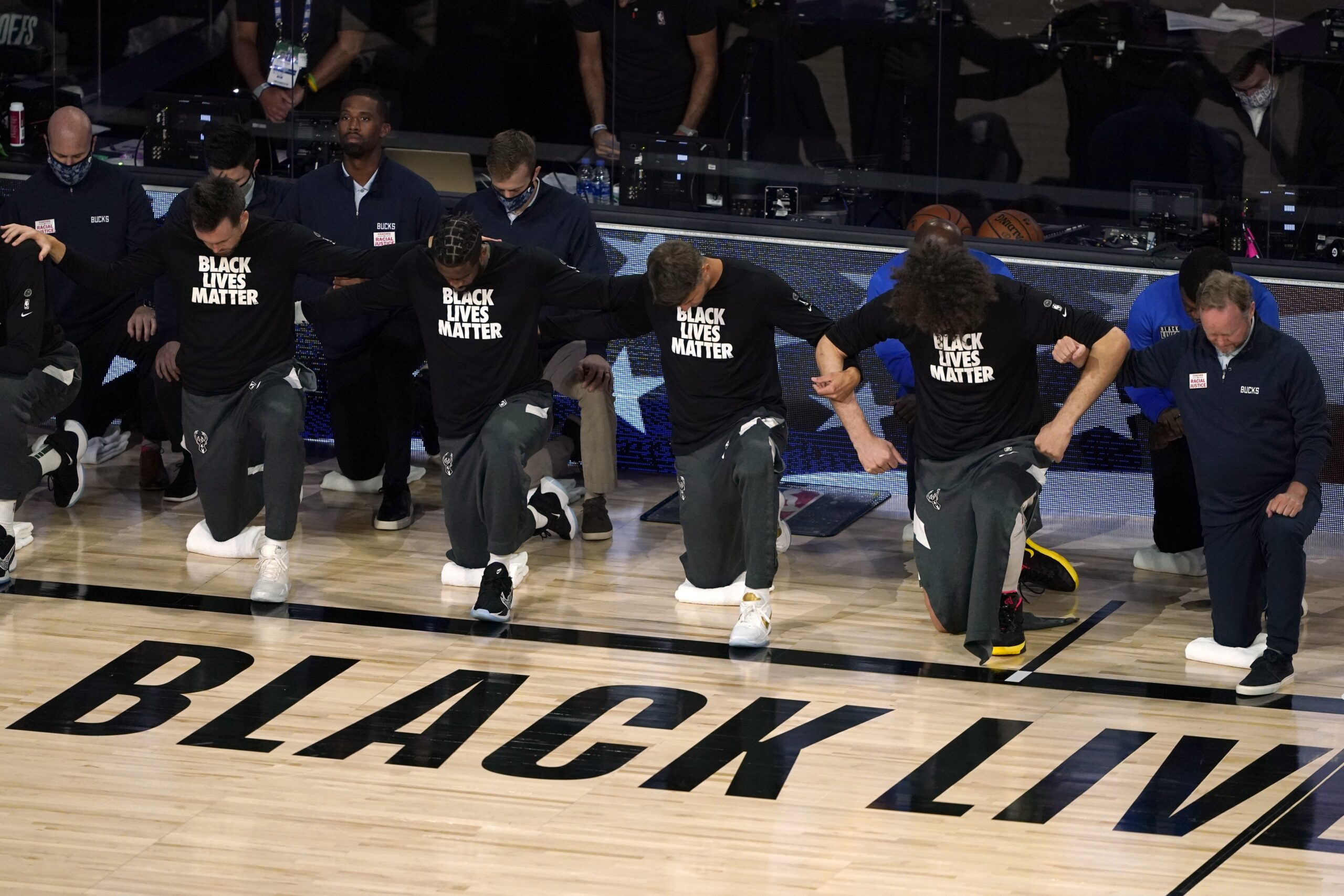 Members of the Milwaukee Bucks join arms as they kneel during the national anthem
