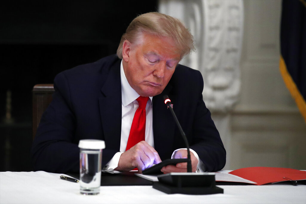 President Donald Trump looks at his phone.