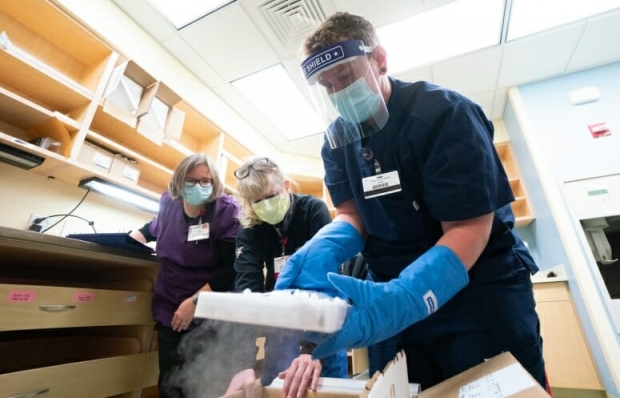 UW Health pharmacy technicians unpack a box of Pfizer's COVID-19 vaccine
