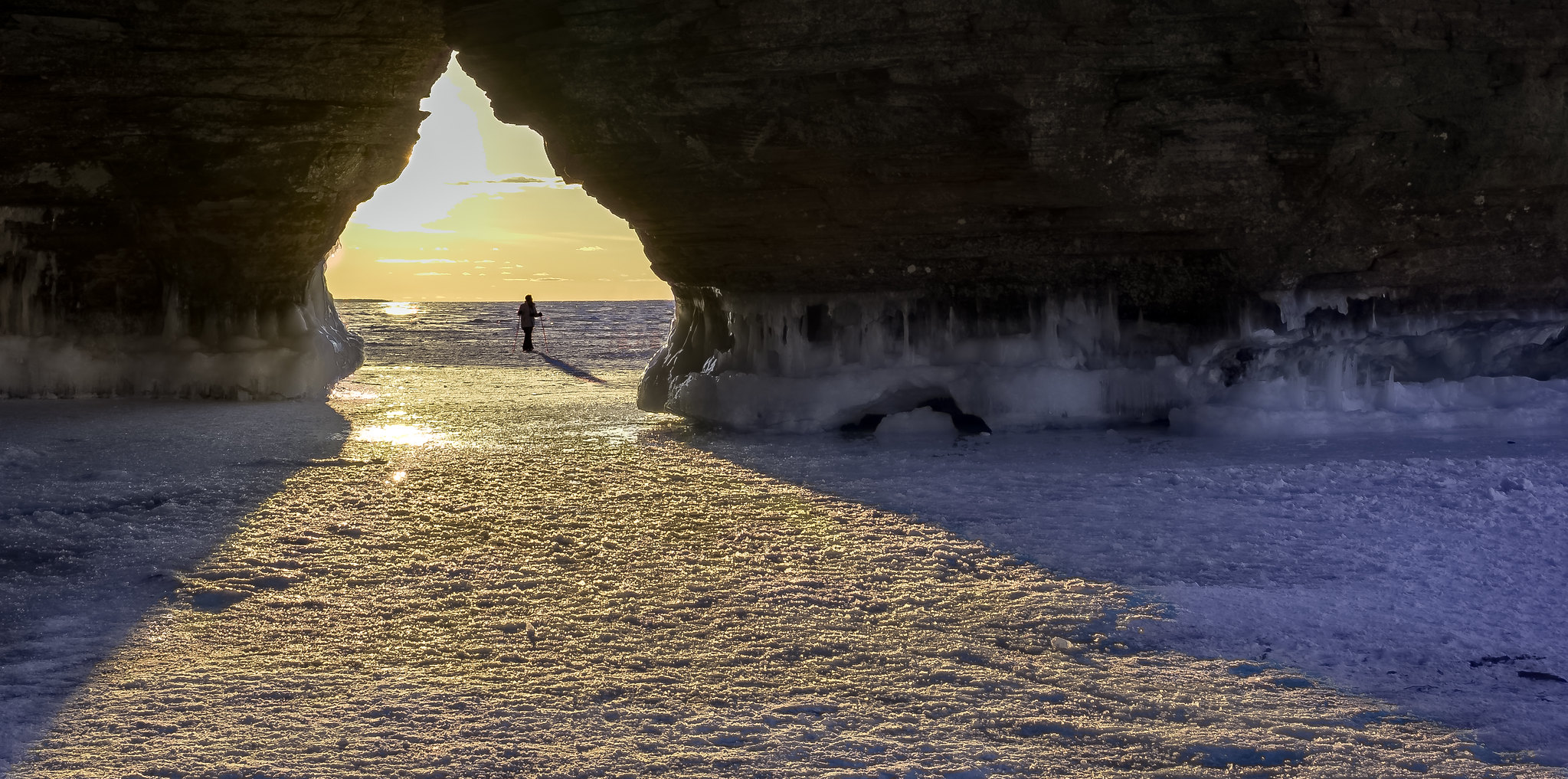 A person is visible in the distance standing between an archway surrounded by frozen surface.