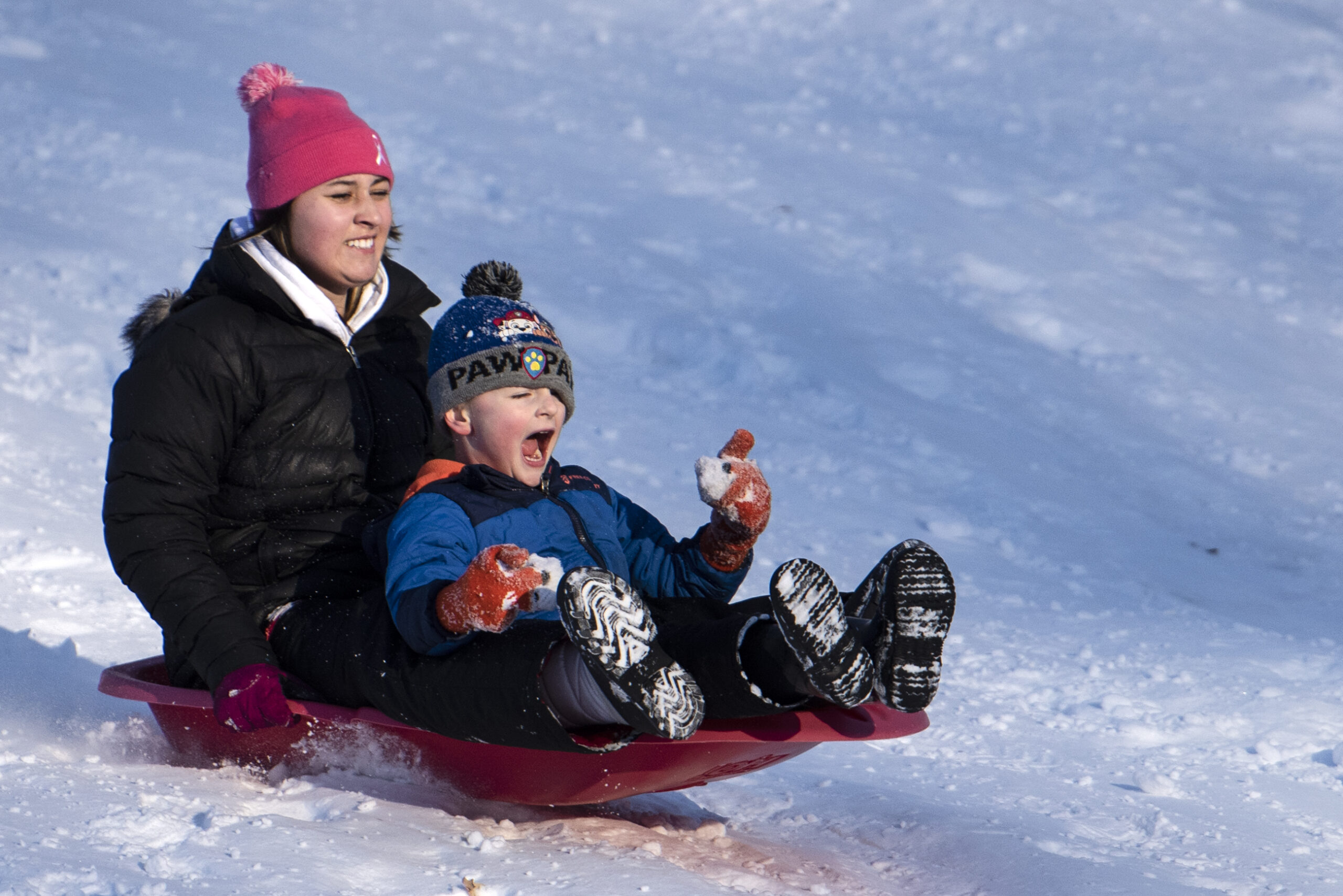 A boy screams as he and his sister hit a bump while sledding down a hill.