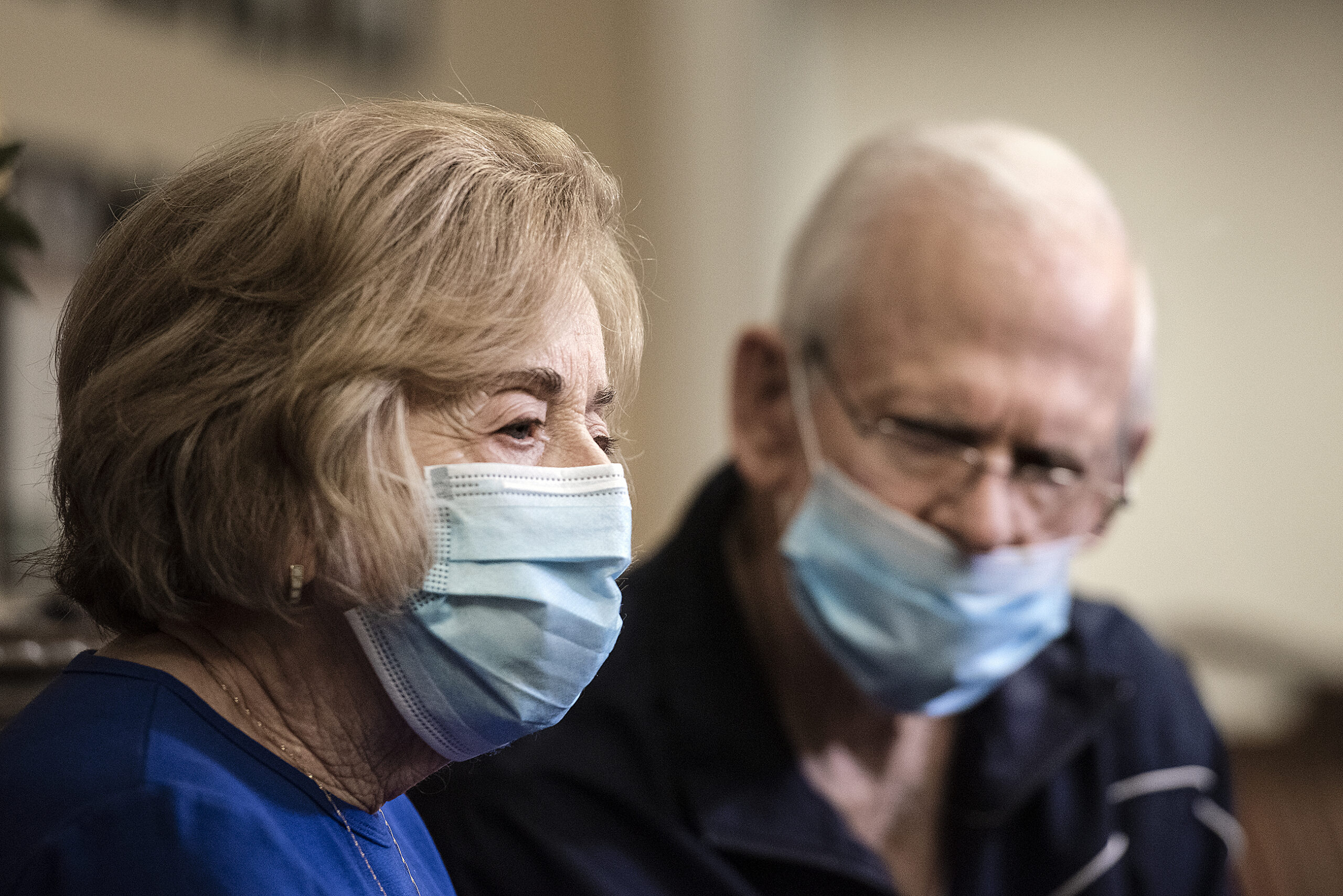 Two people in face masks sit near one another