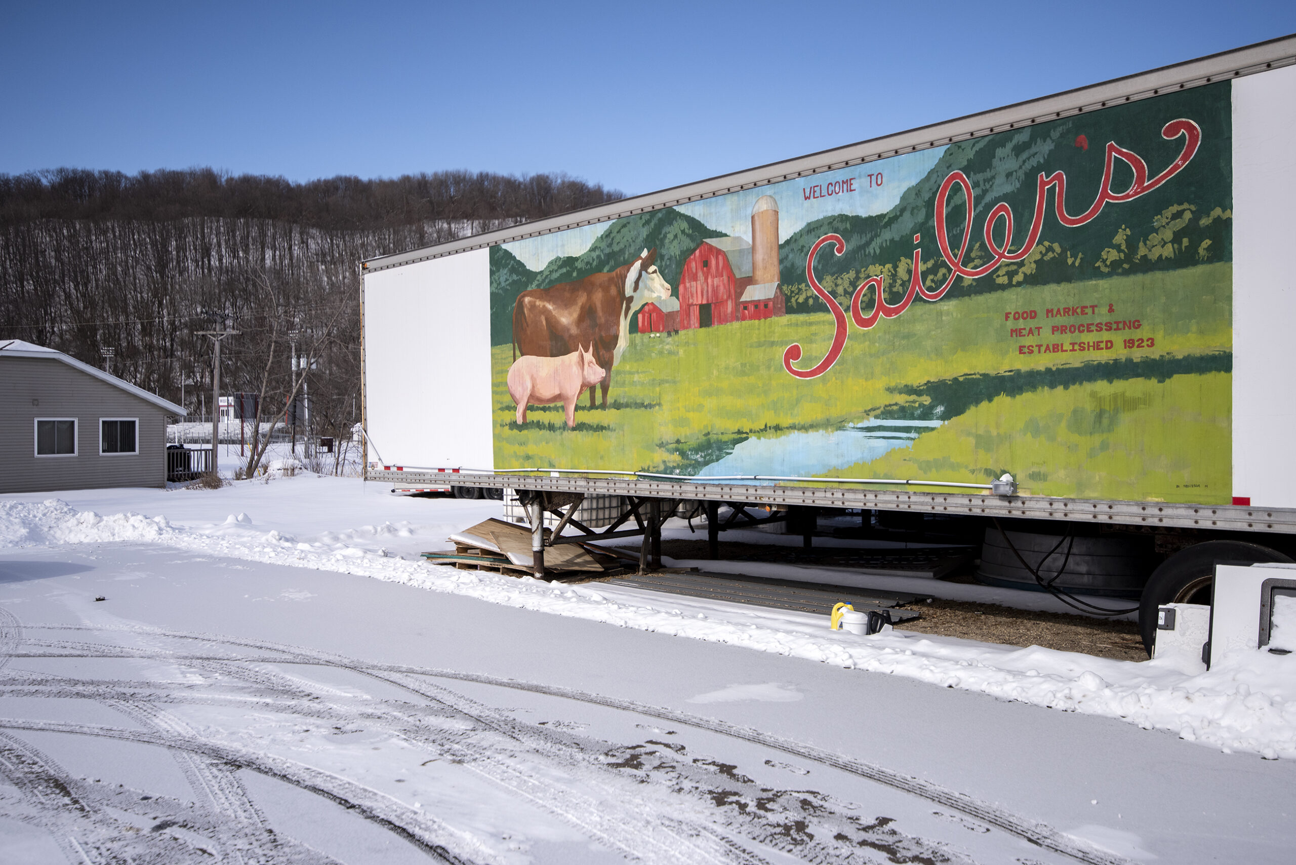 A large trailer has a farm scene and the words 