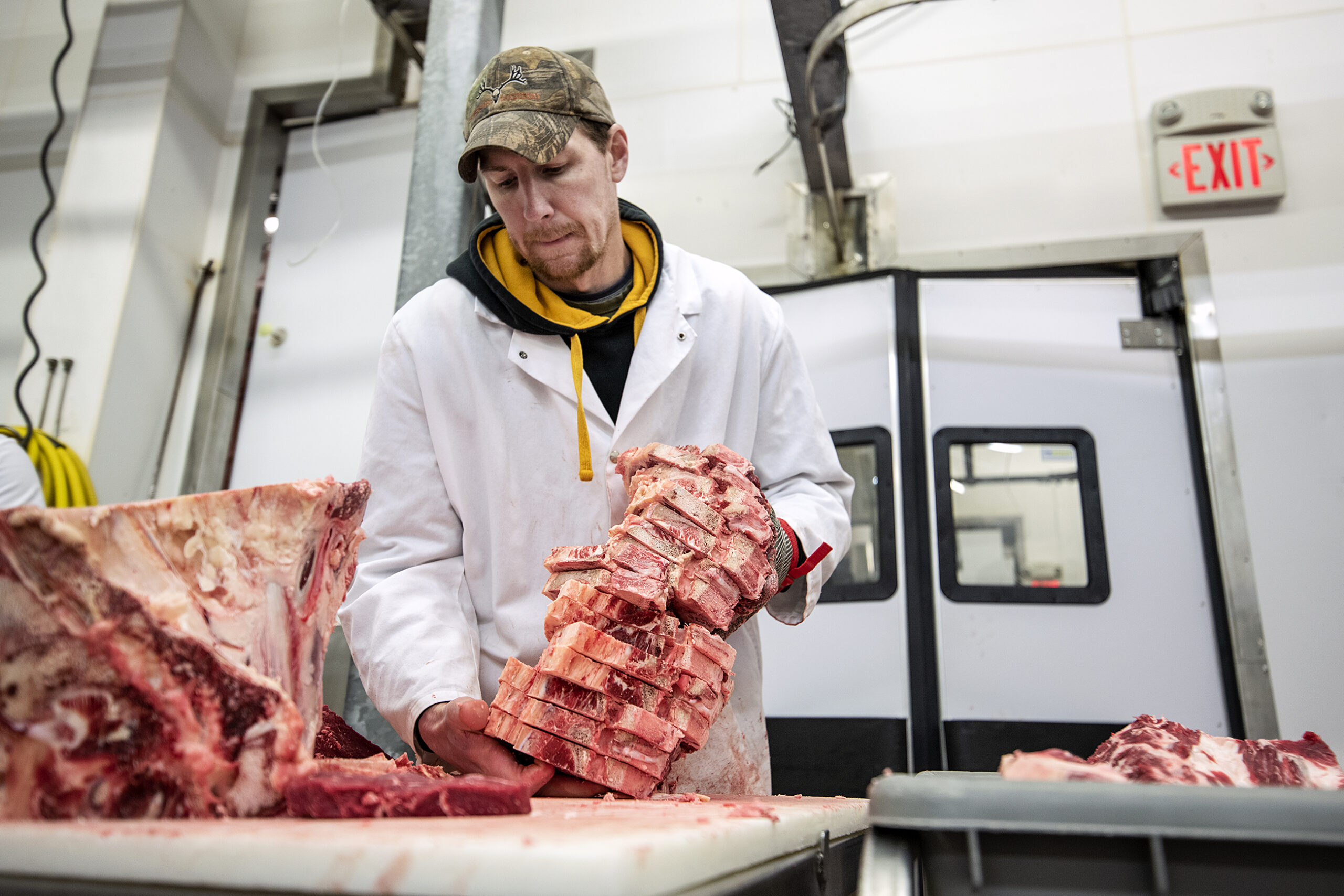 A worker picks up a tall stack of 17 T-Bone steaks