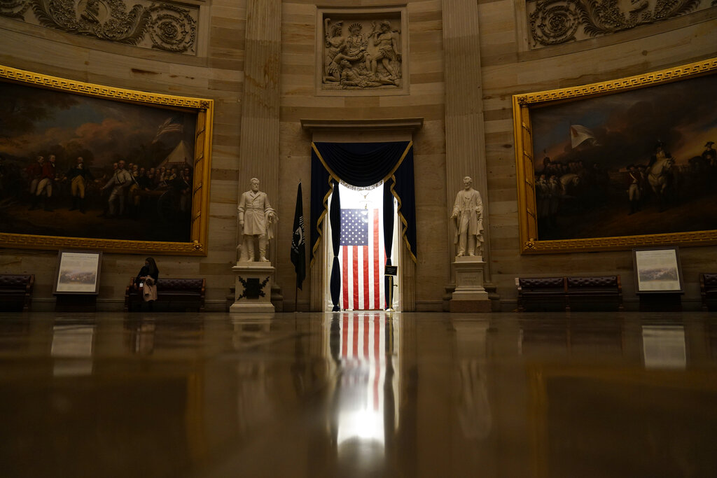 Light shines on an American flag as seen from the Capitol Rotunda in Washington, Wednesday, Jan. 13, 2021