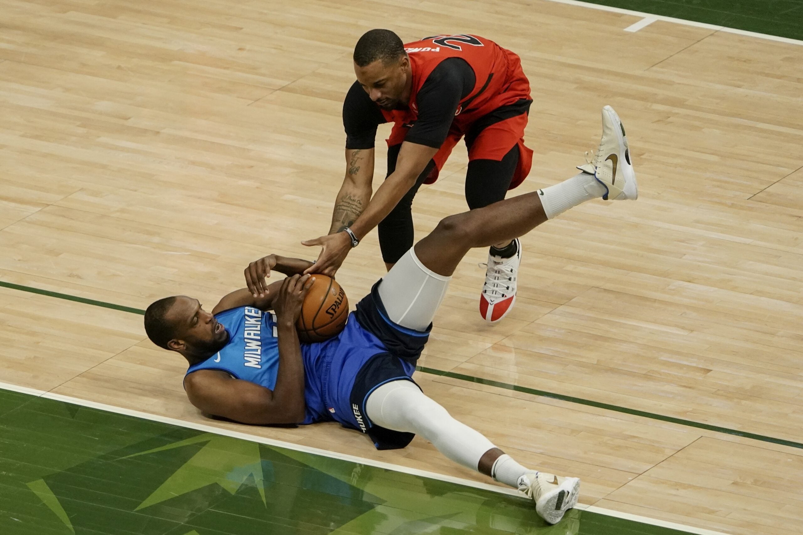 Milwaukee Bucks' Khris Middleton and Toronto Raptors' Norman Powell go after a loose ball