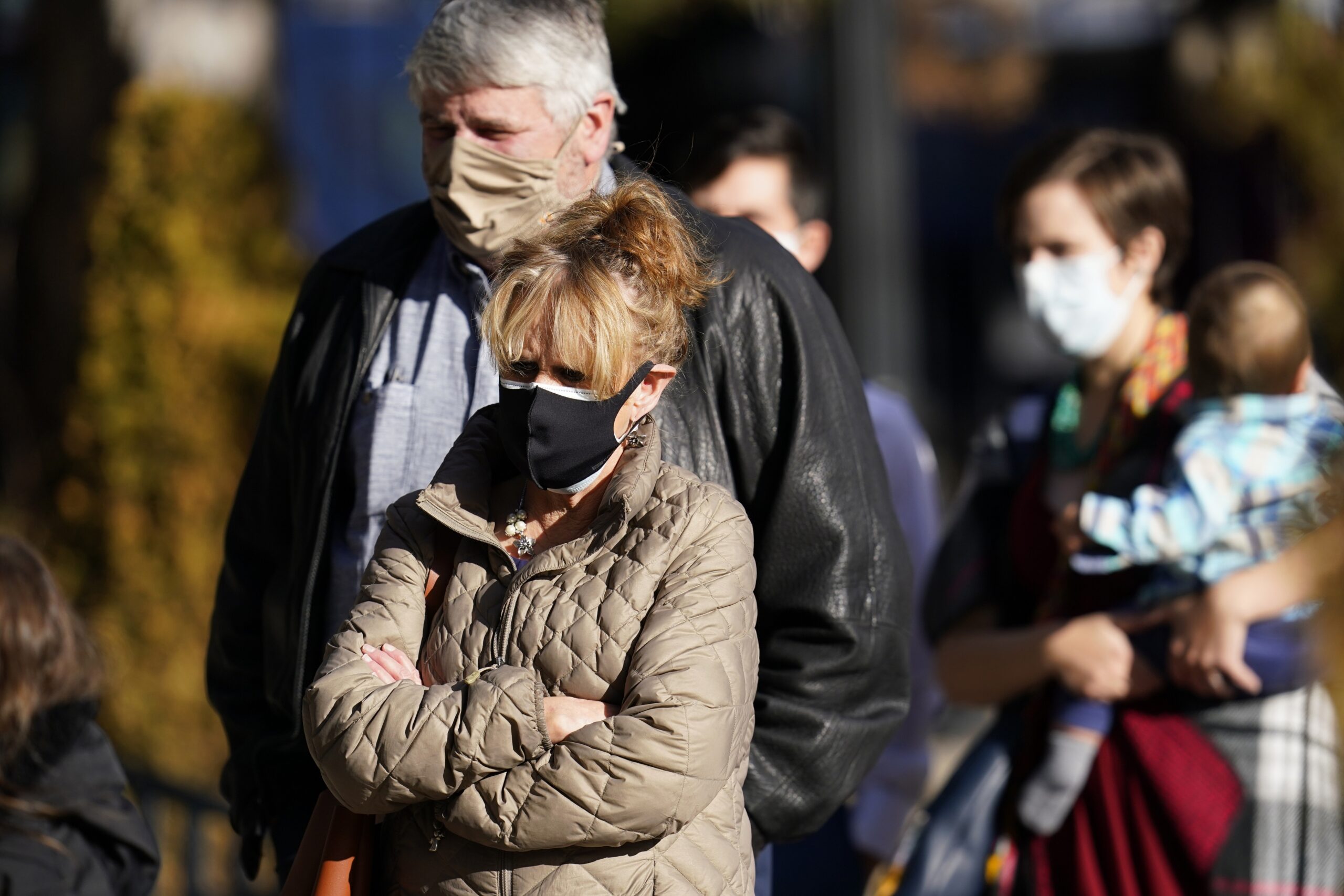 People wearing masks line up outdoors