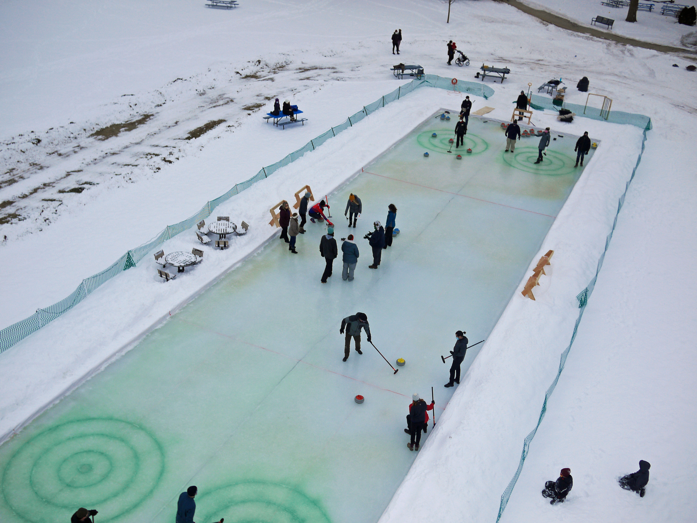 Curlers practice skills on a built-in sheet of ice at a park in Monona