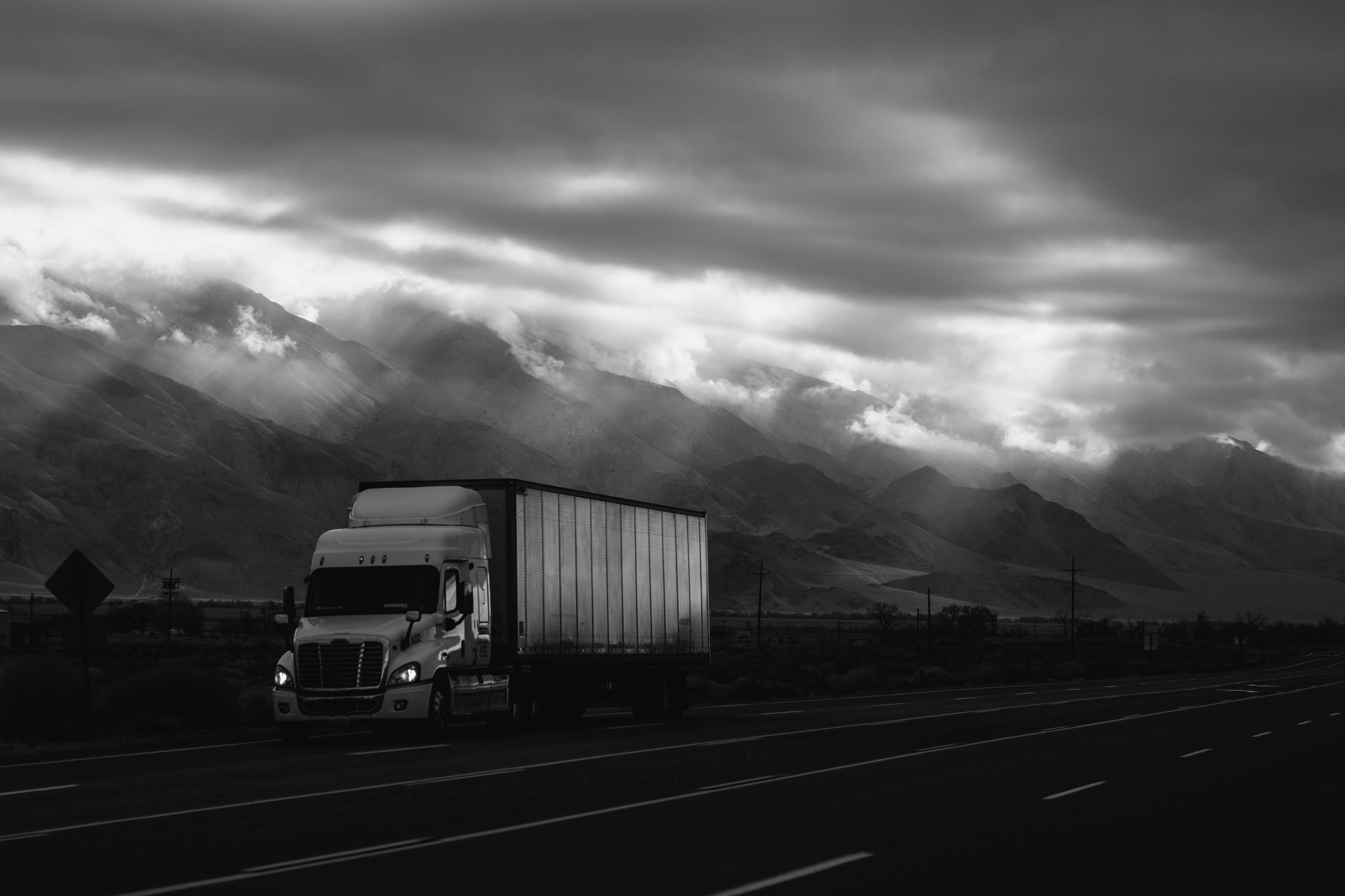 A truck driving in front of mountains shrouded in fog