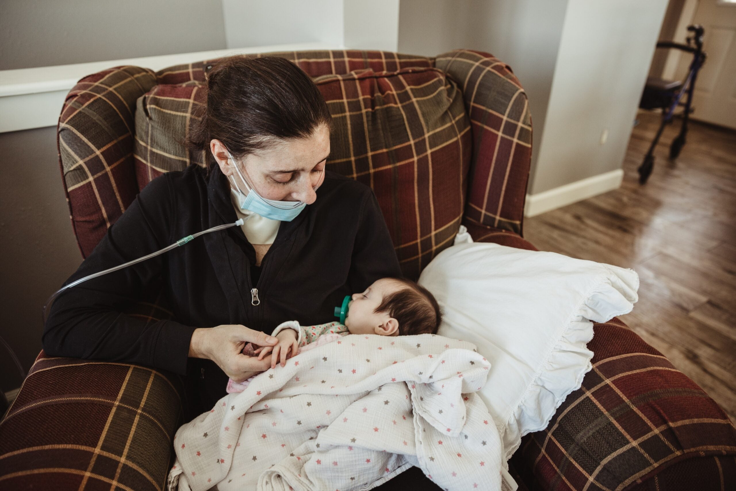 Woman in mask holds young baby