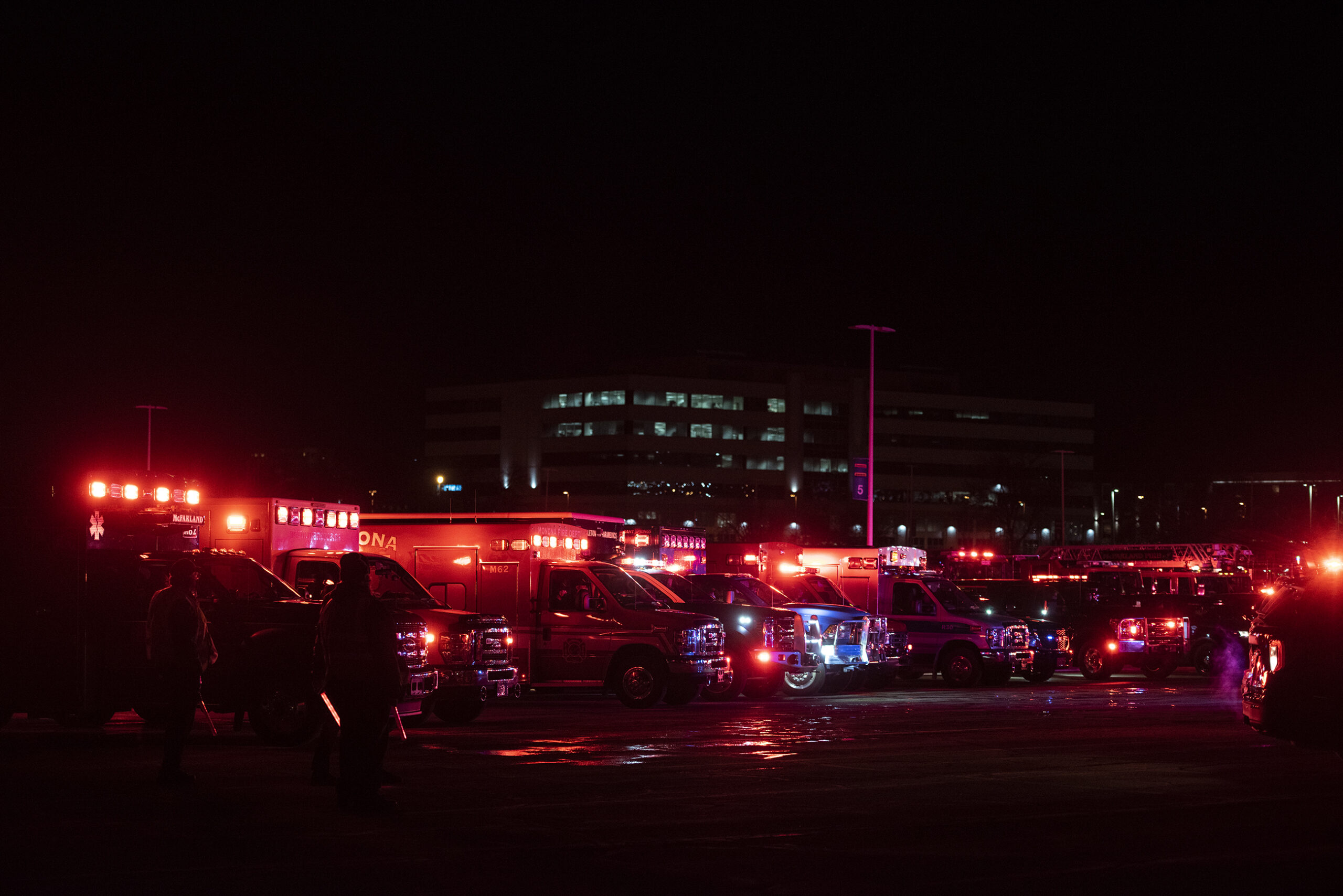 Several lights from emergency vehicles fill the dark night sky with red light.