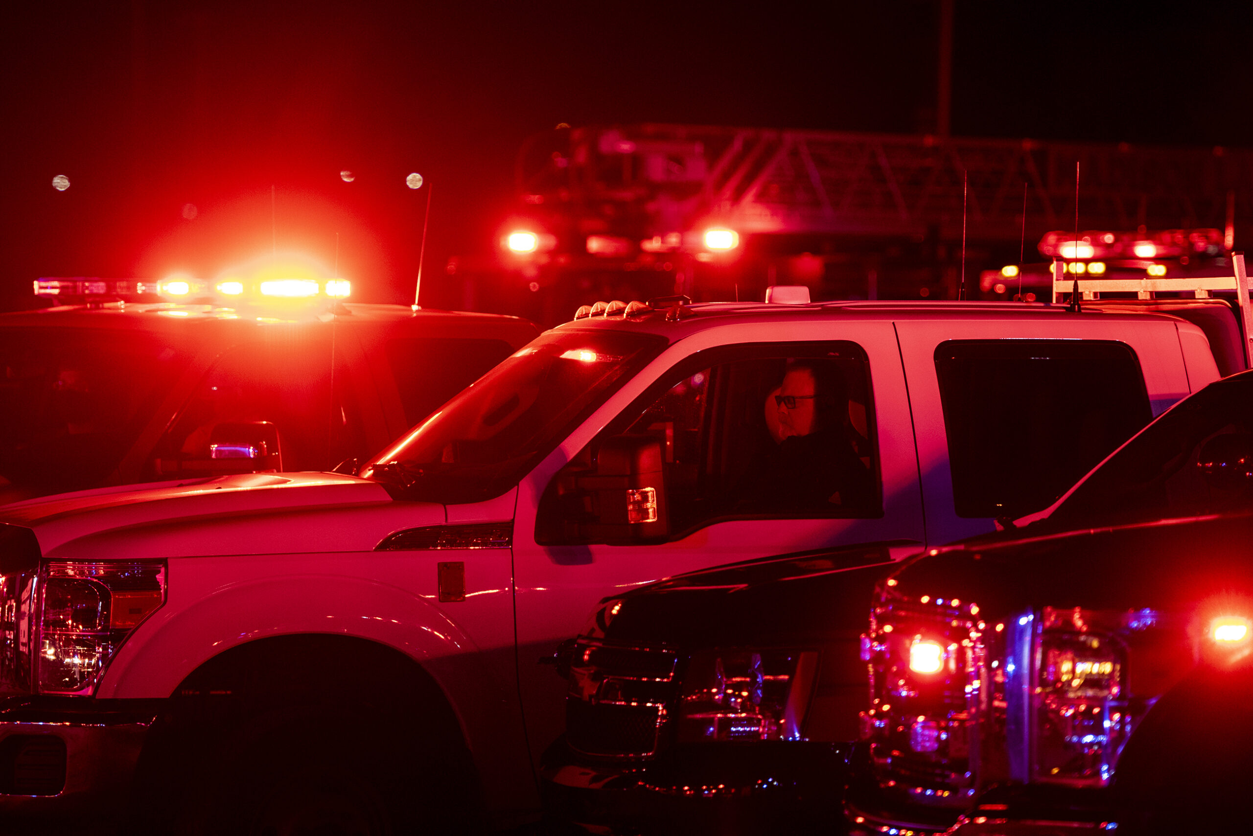 A white truck is lit up with red lights as a man sits inside.