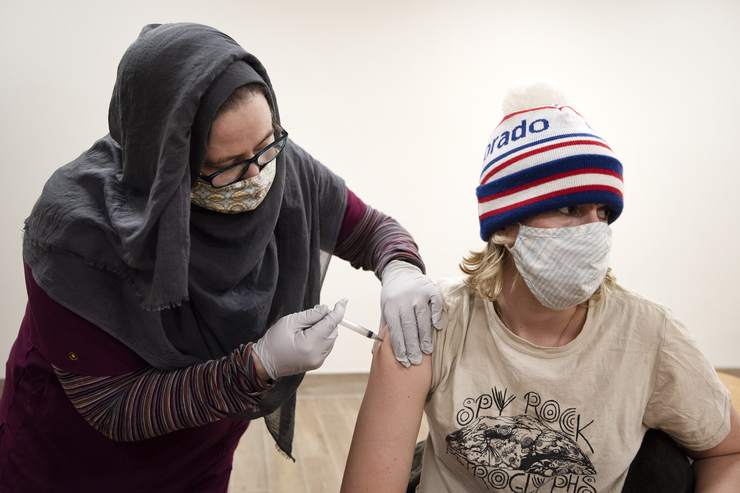A woman with a sleeve pushed up looks away as she receives a vaccine.
