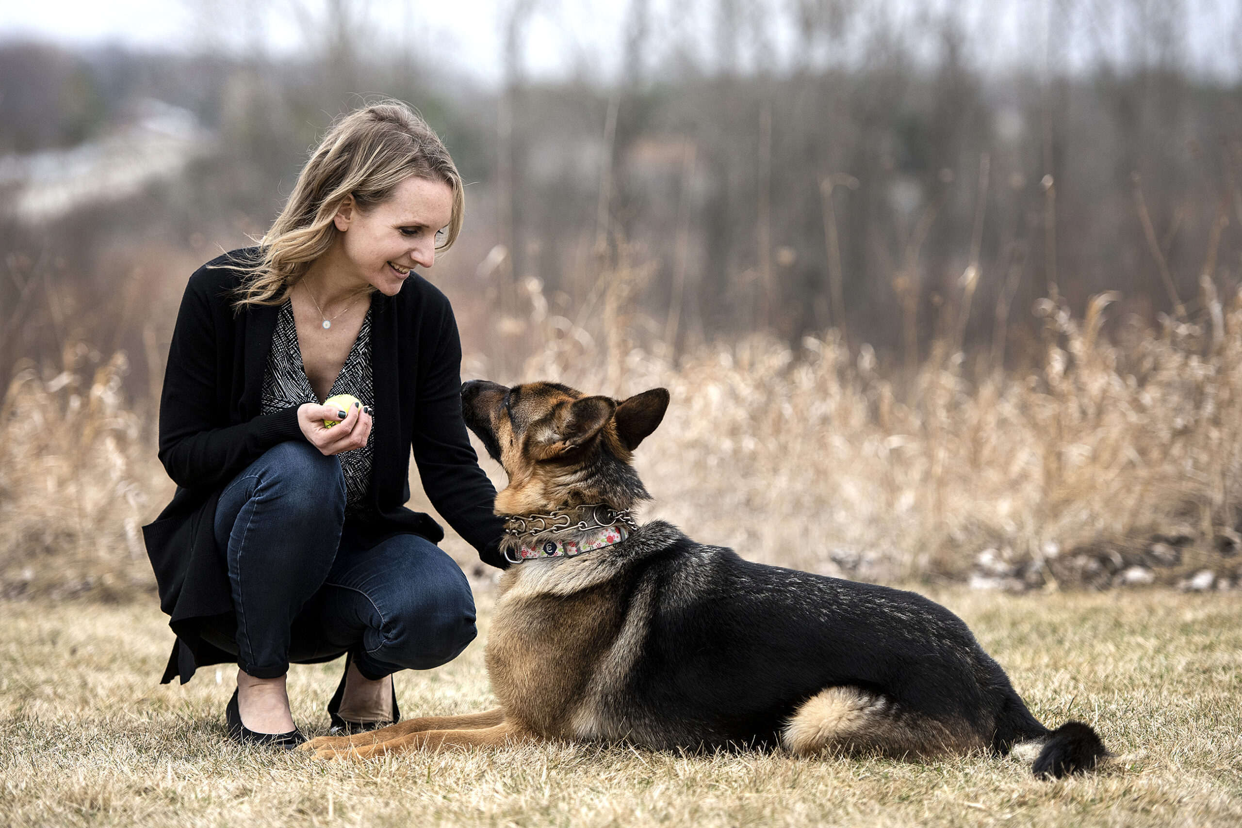 A woman squats to pet a German Shepherd.