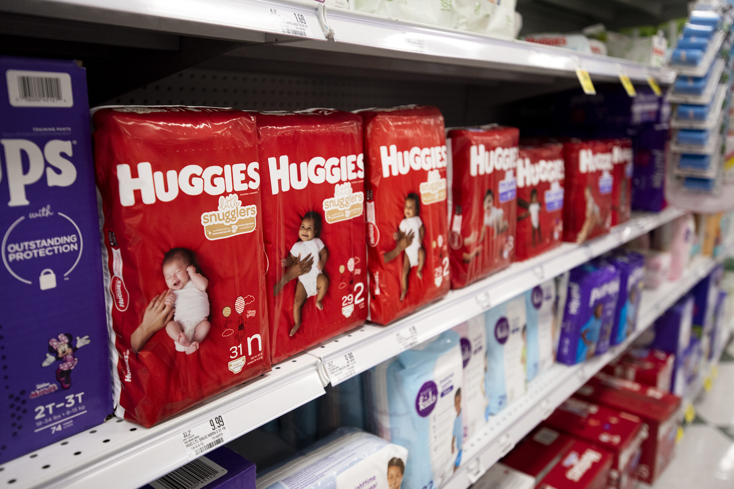 Red packages of Huggies diapers are on a shelf.