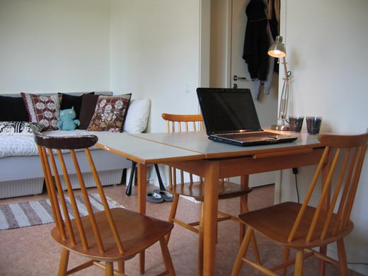 A laptop sits open on the kitchen table with a lamp nearby.