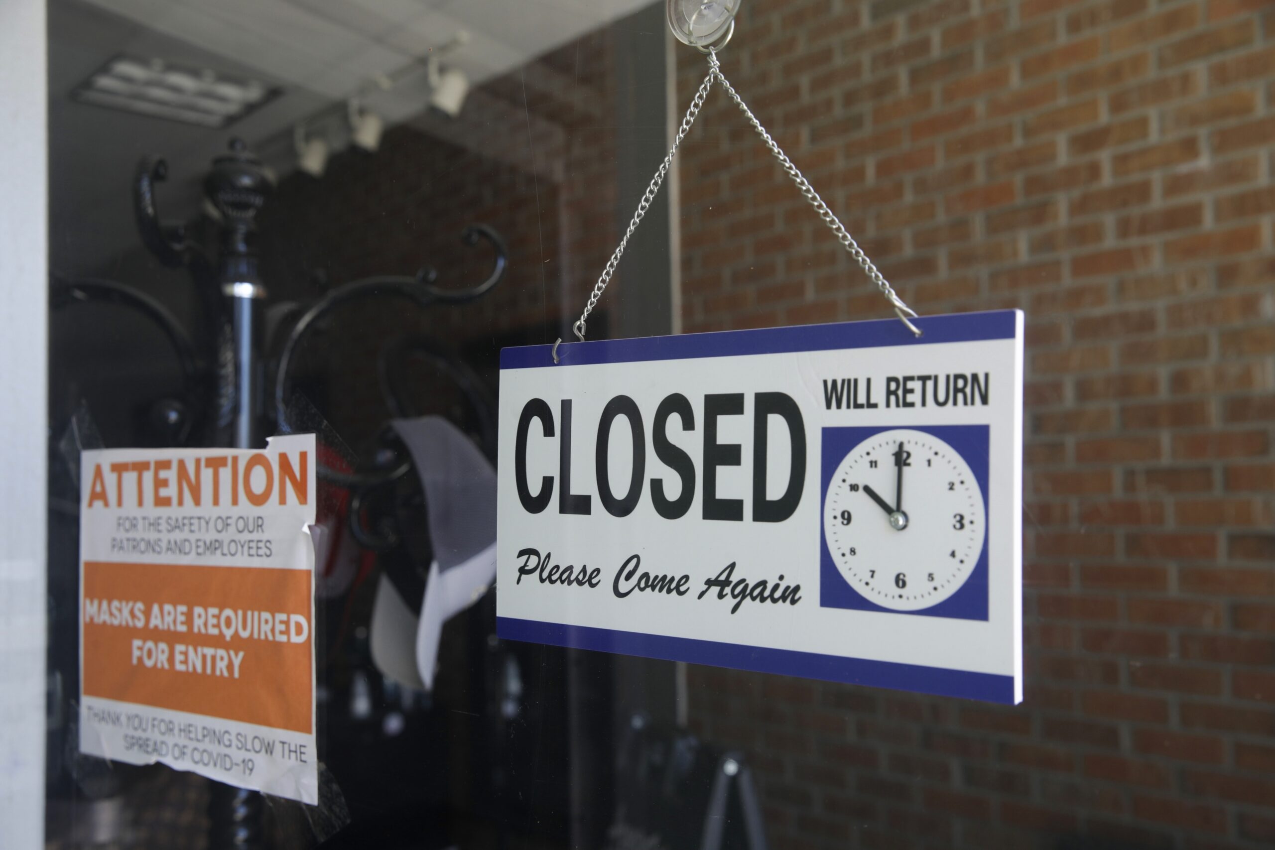 A closed sign hangs in the window of a barber shop