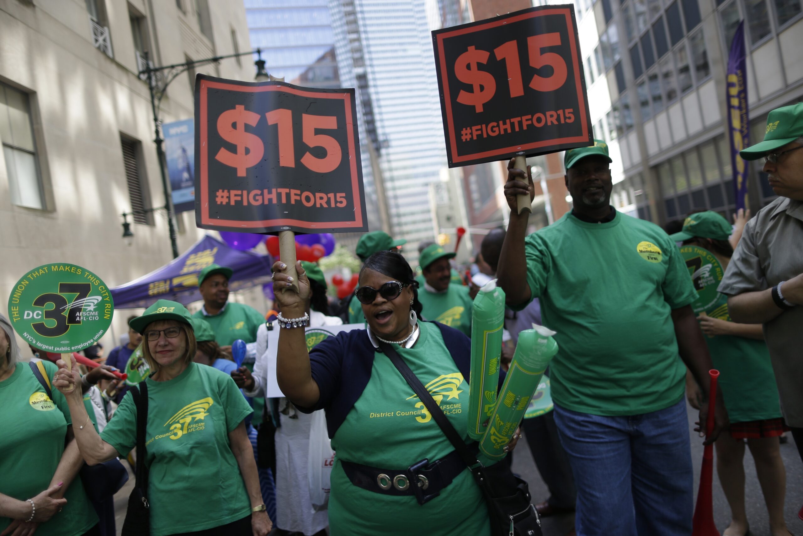 Activists hold signs in support of $15 minimum wage