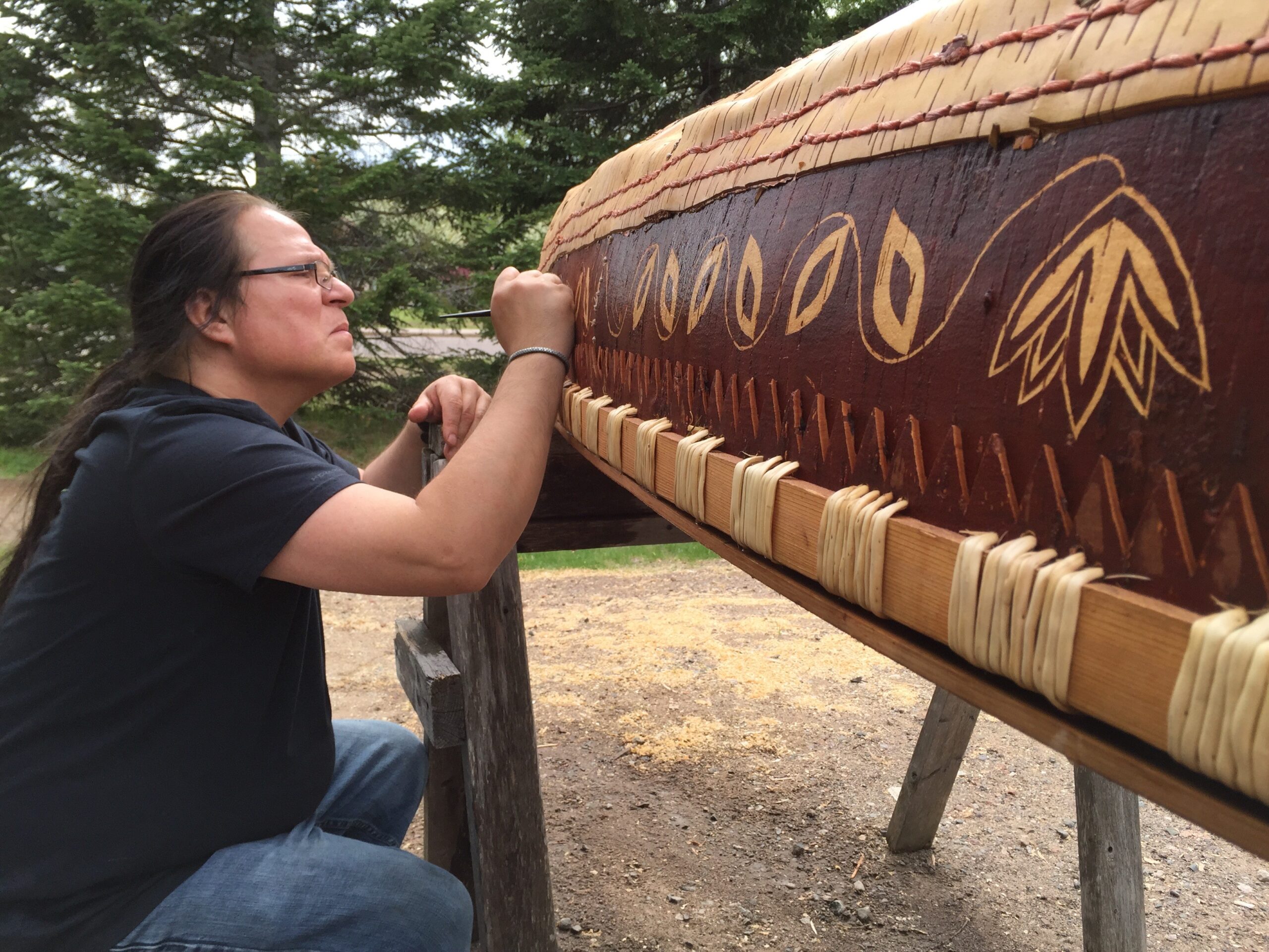 Wayne Valliere adds detail to a birchbark canoe he built