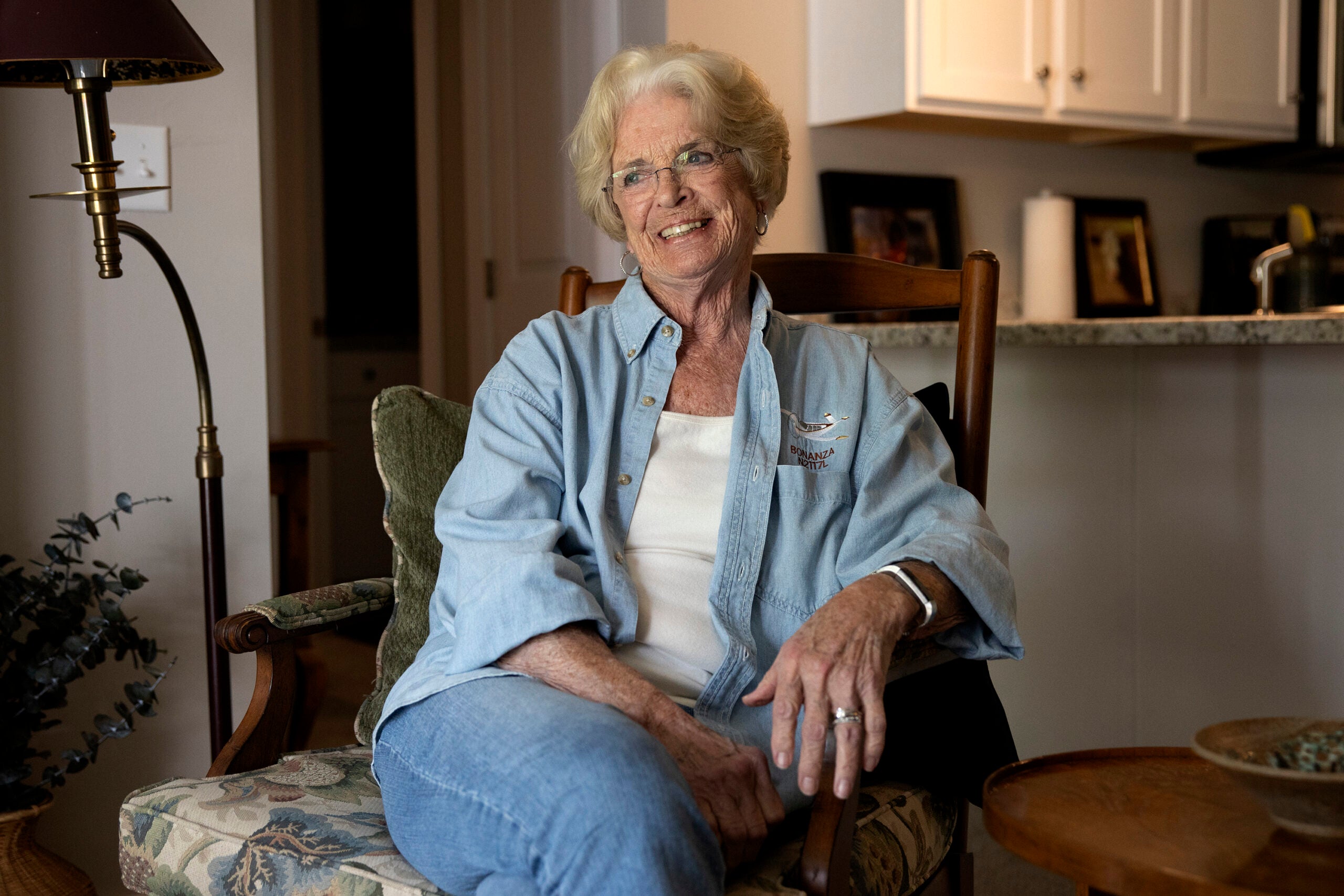 An older woman sits in a chair in her living room
